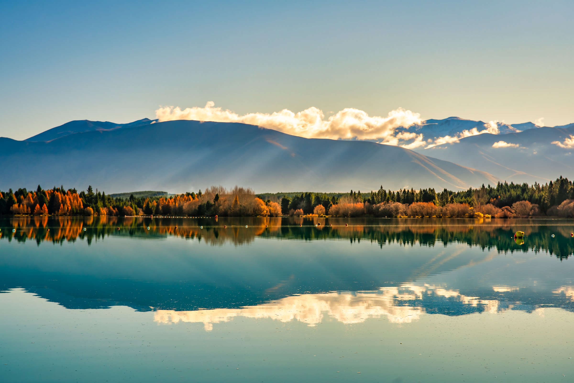 The snow capped Southern Alp peaks reflected on on the still calm water of the rowing course at Lake Ruataniwha in NZ South Island