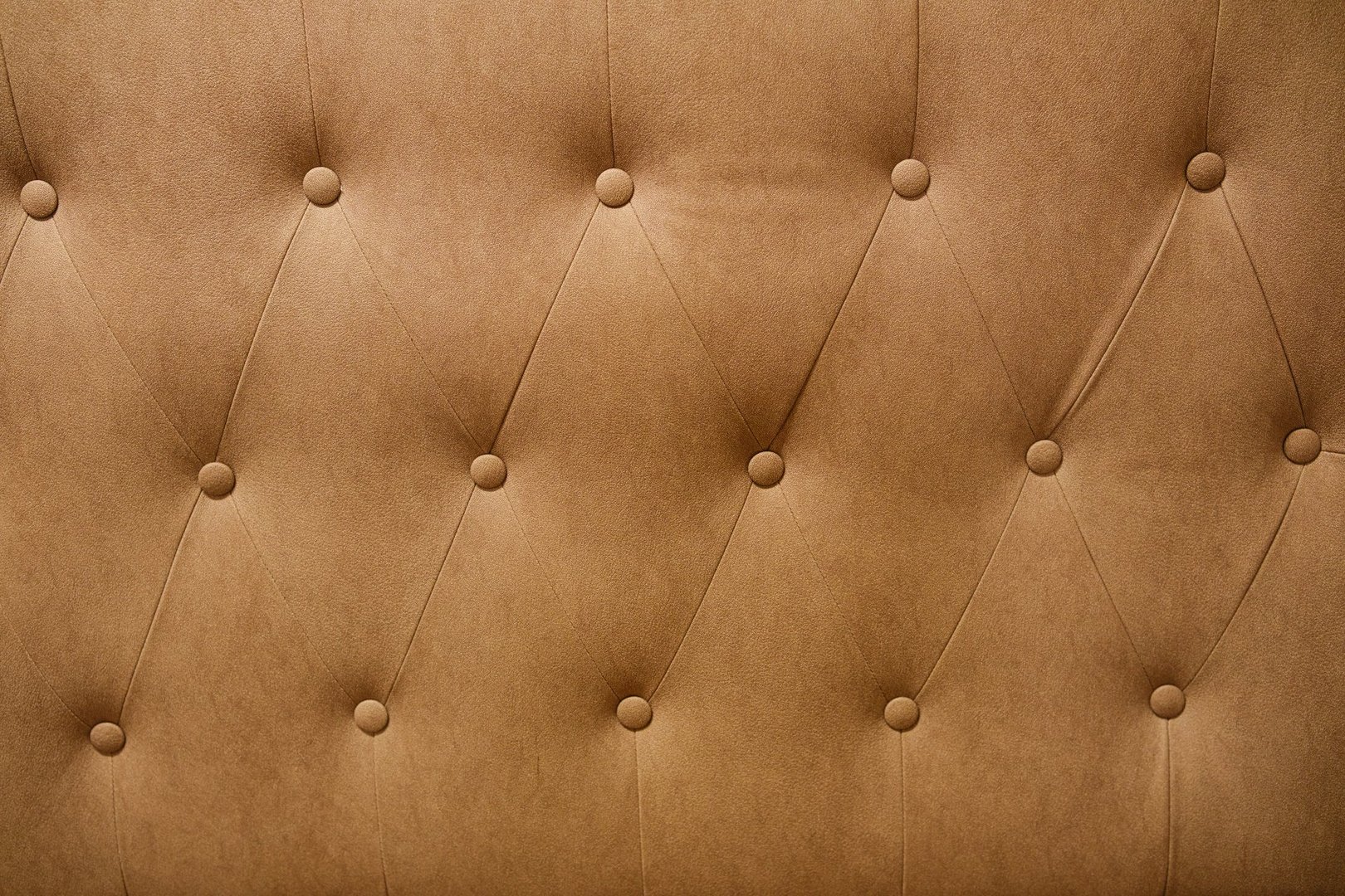 Brown textured fabric surface with button tufting detail