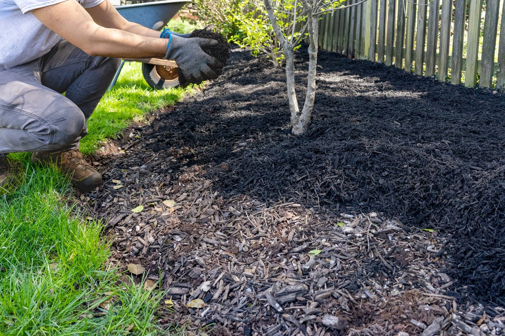 Man tosses handfuls of mulch into a prepared bed