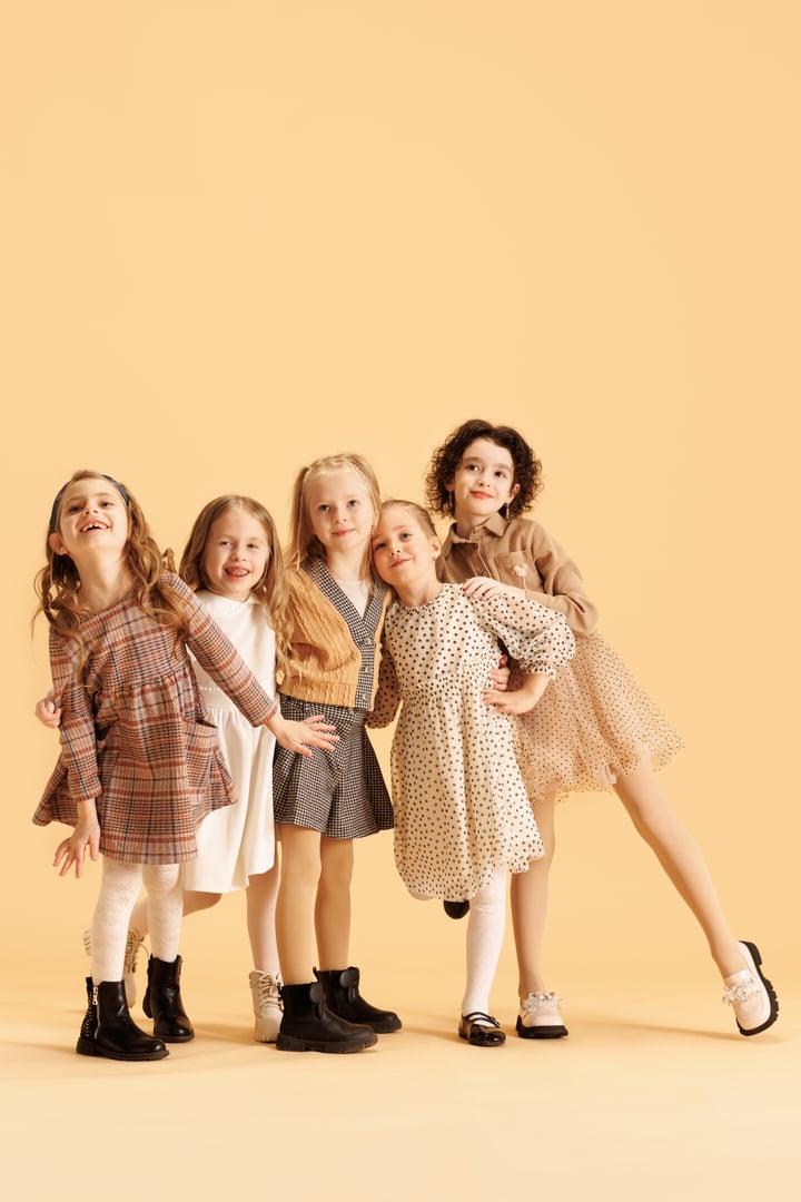 Cute girls, friends posing dressed trendy clothes with stylish hairstyles against beige studio background. Elegant young ladies. Concept of fashion and style, Black Friday, sales season, shopping.