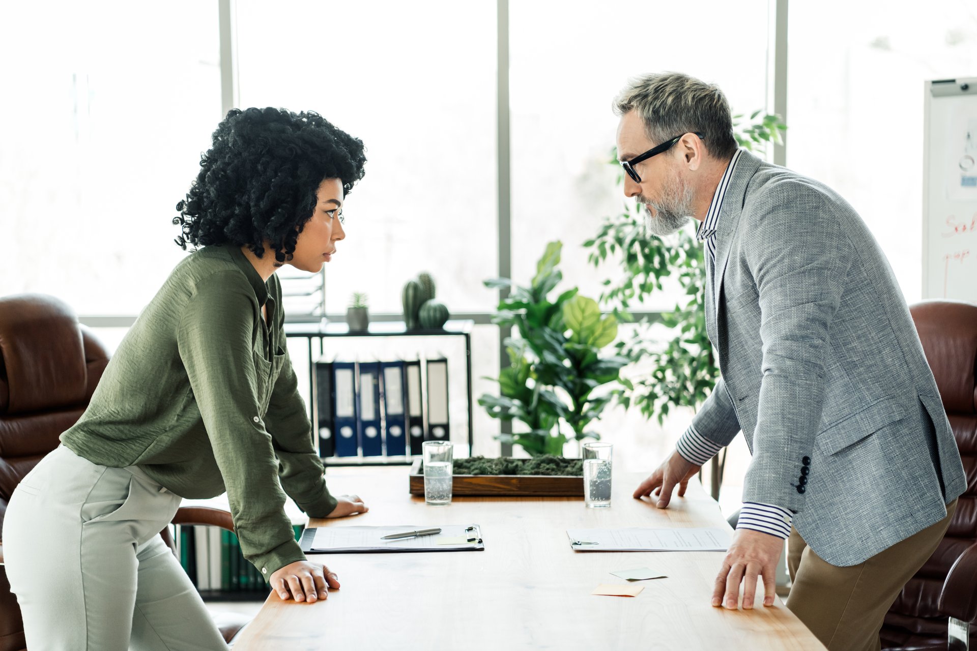 Focused business colleagues in a discussion at the office. A coworking environment highlighting cooperation, professionalism, and diversity as they strategize around a shared table. Modern, elegant workspace fostering teamwork and collaboration.