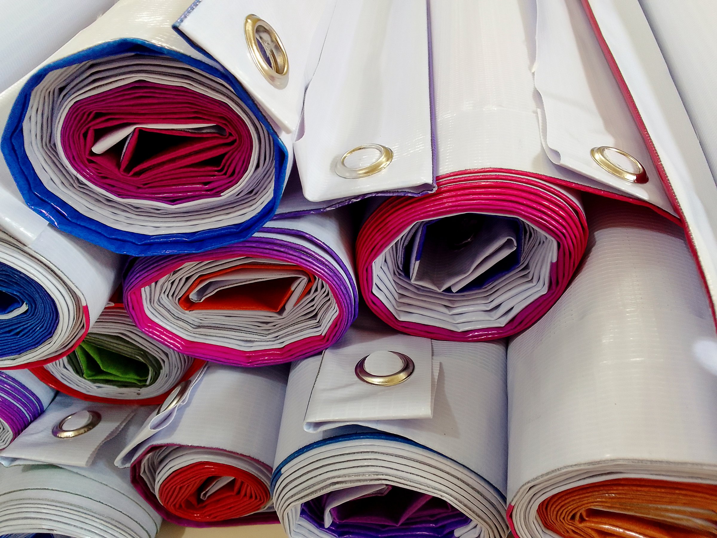 digital printed banner. a group of rolled up banners in the printing industry. stack of packaged products in work space. white tarpaulin printed with colorful colors