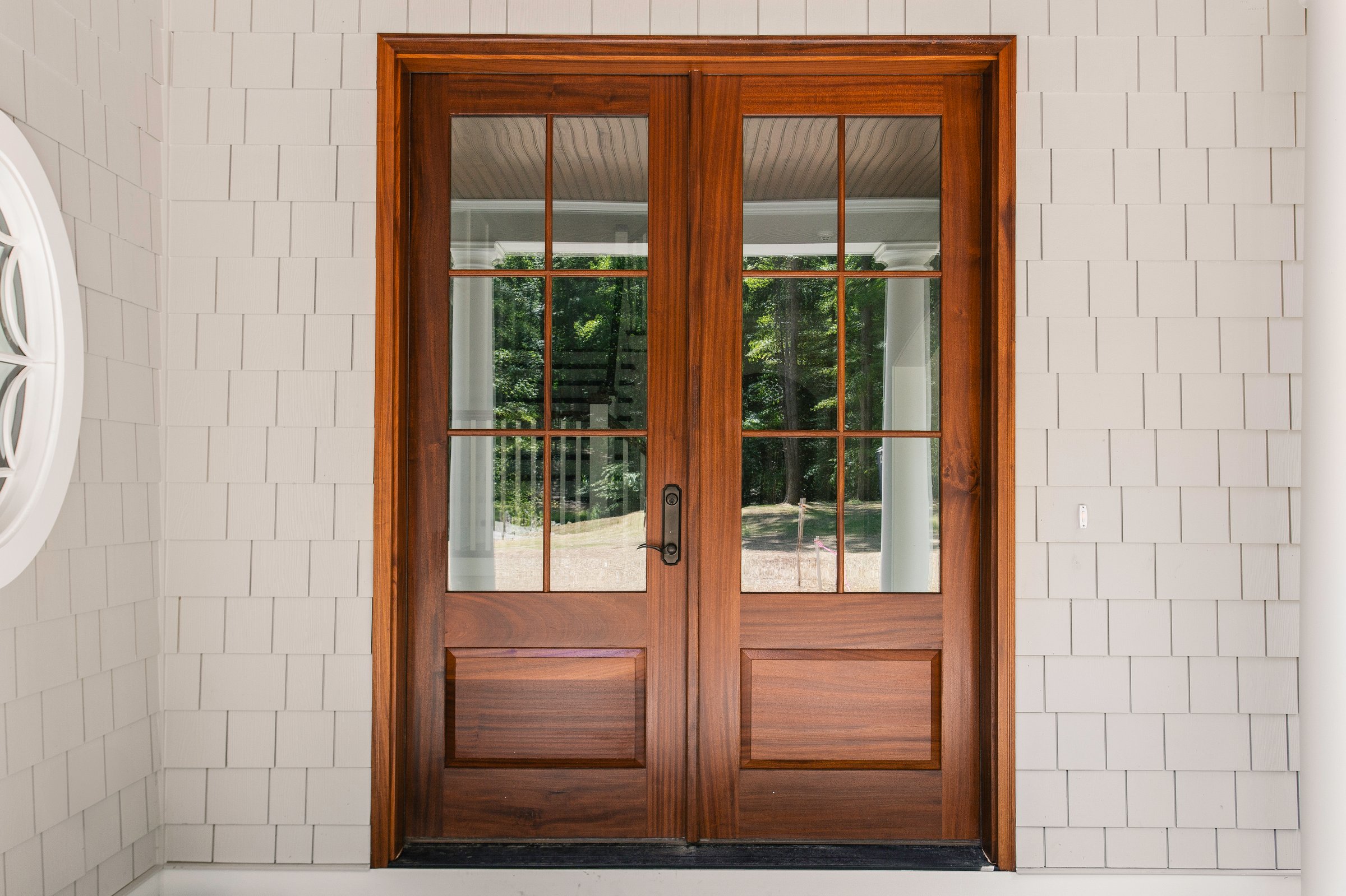 Elegant wooden double doors with glass panes leading to a porch area