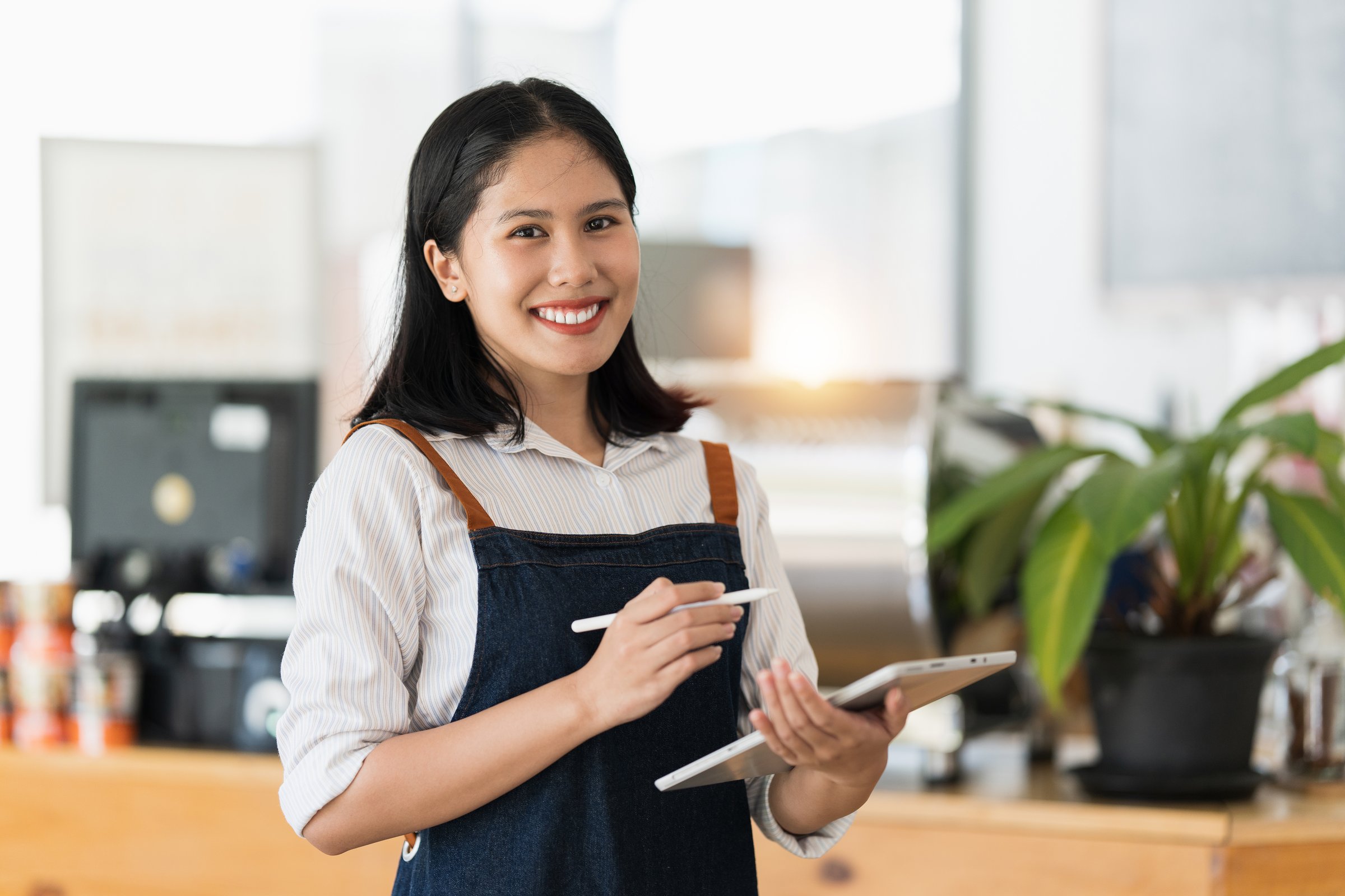 Asian cafe owner or barista standing with smiling at cafe. woman small business owner in food and beverage.
