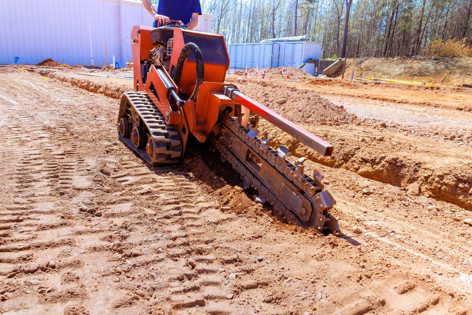 Heavy trenching machinery digs trench in soil for construction purposes on work site