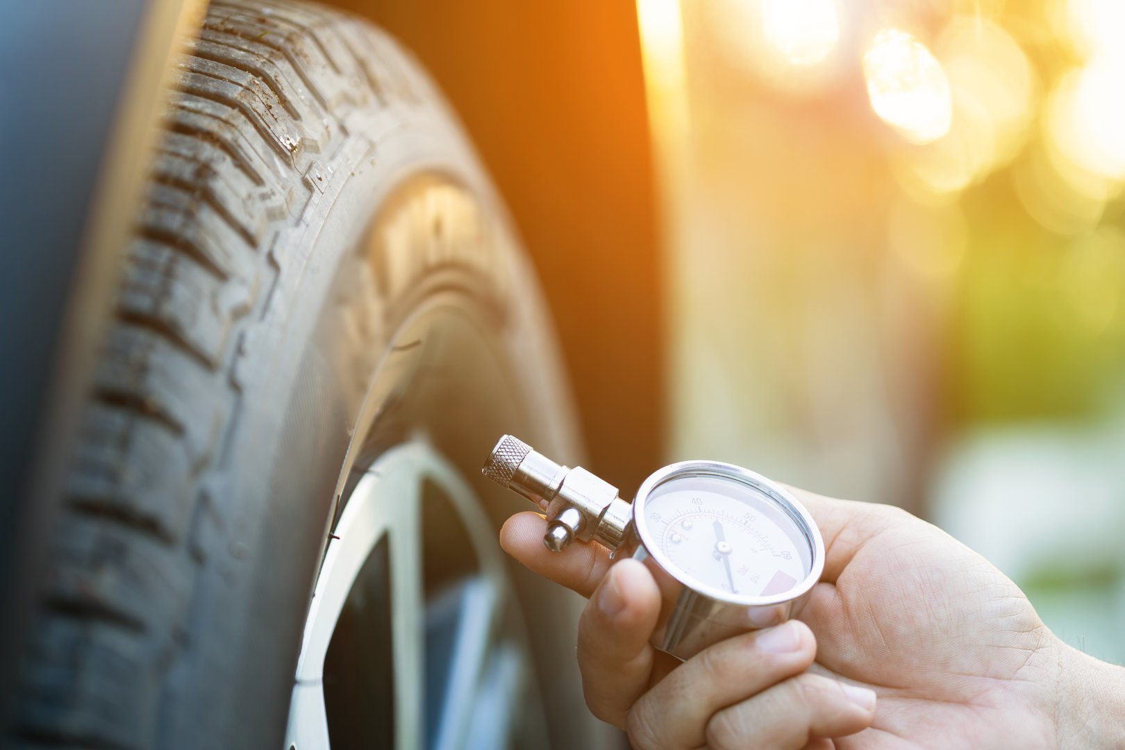 A car owner uses a pressure gauge to check tire inflation, emphasizing vehicle readiness and the importance of proper tire maintenance before embarking on a journey
