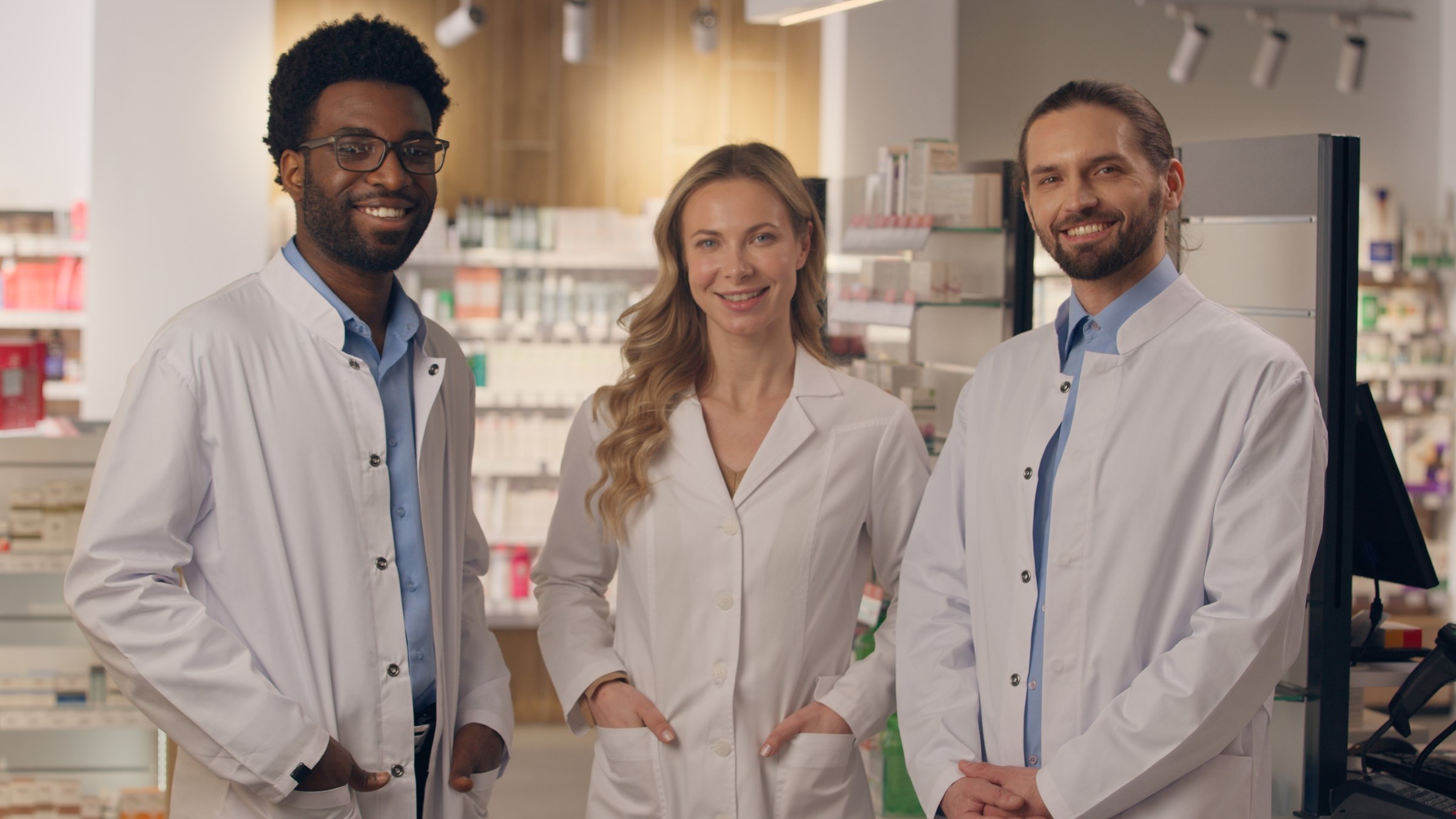 Multiracial people team doctors men woman in pharmacy drugstore professional health care workers in medical coats pharmacist physician therapist team African Caucasian male female looking at camera. High quality 4k footage