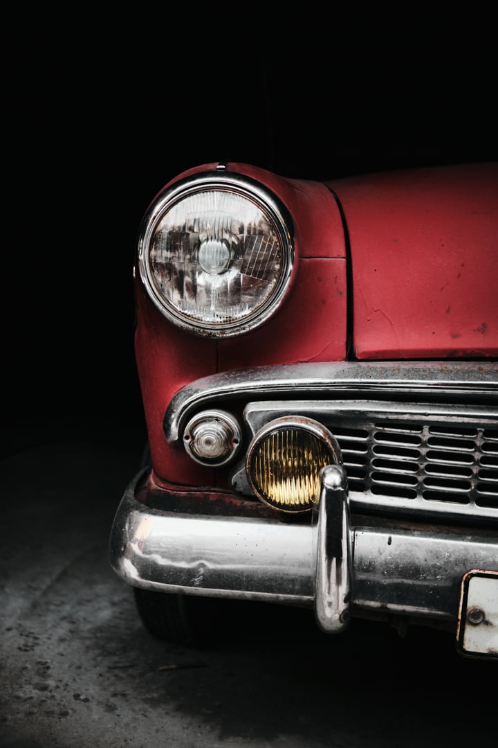 Close-up detail of red vintage car headlight with chrome bumper retro automotive design