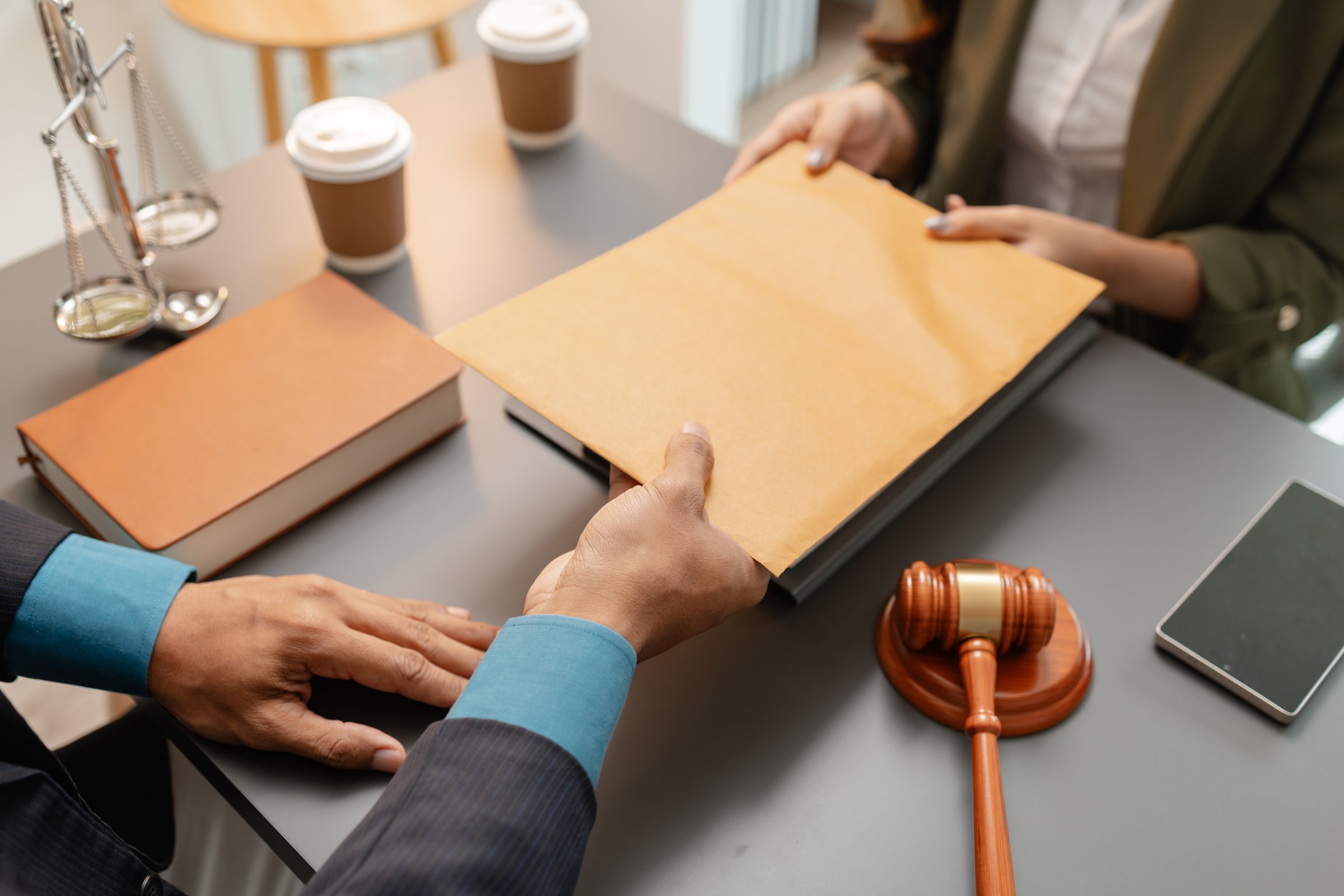 A lawyer and a client exchange a brown envelope across a desk, symbolizing confidential legal documents or evidence sharing. The setting includes legal symbols such as a gavel and scales of justice.