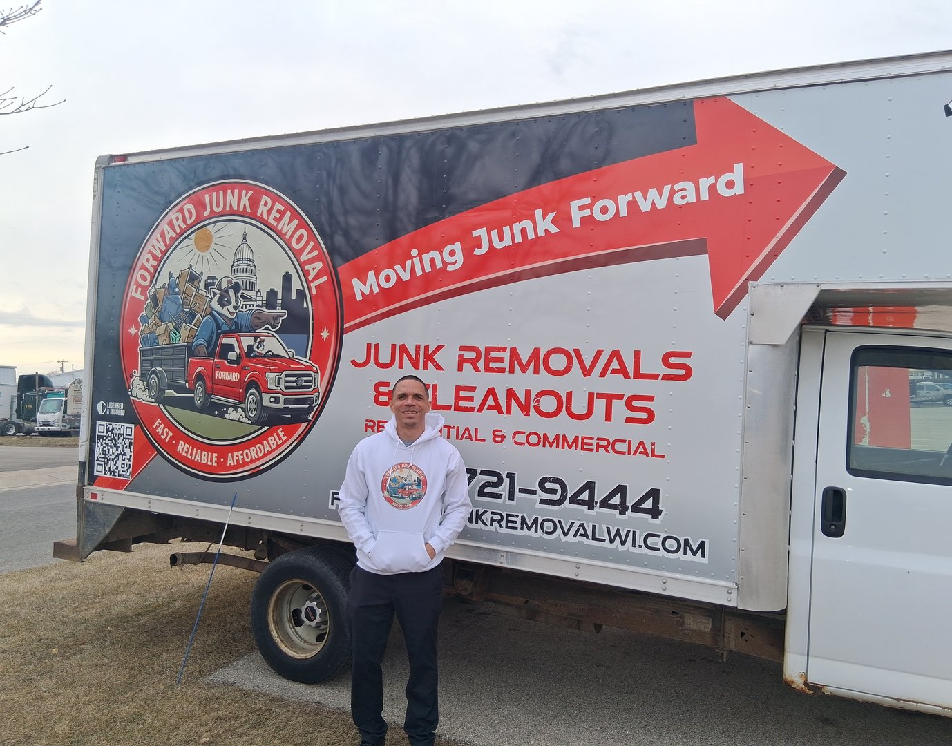 Owner standing in front of Forward Junk Removal wrapped box truck