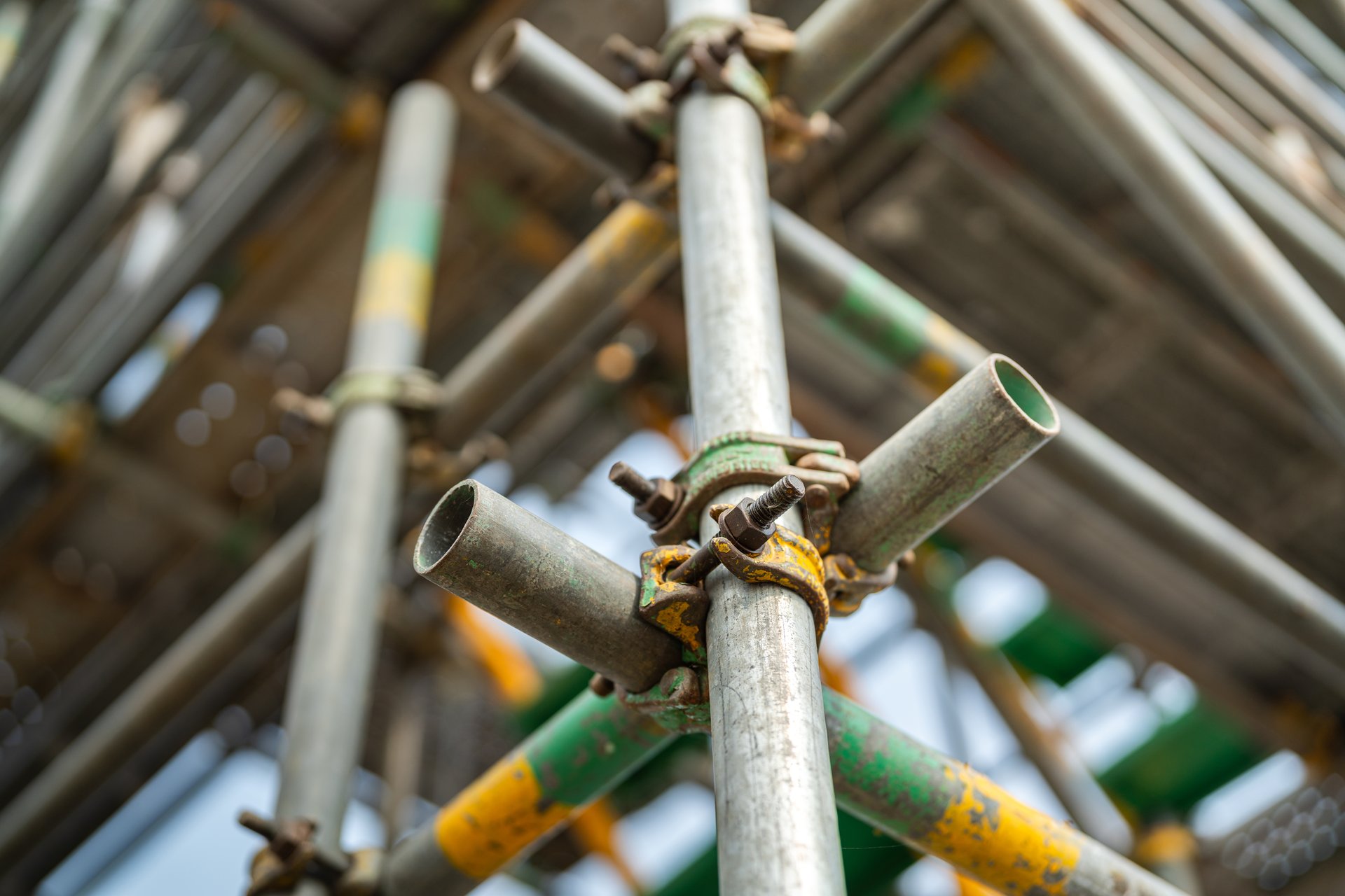 Close-up at metal pipe connection joint of the working platform scaffold at the construction work site. Industrial equipment and object, selective focus.