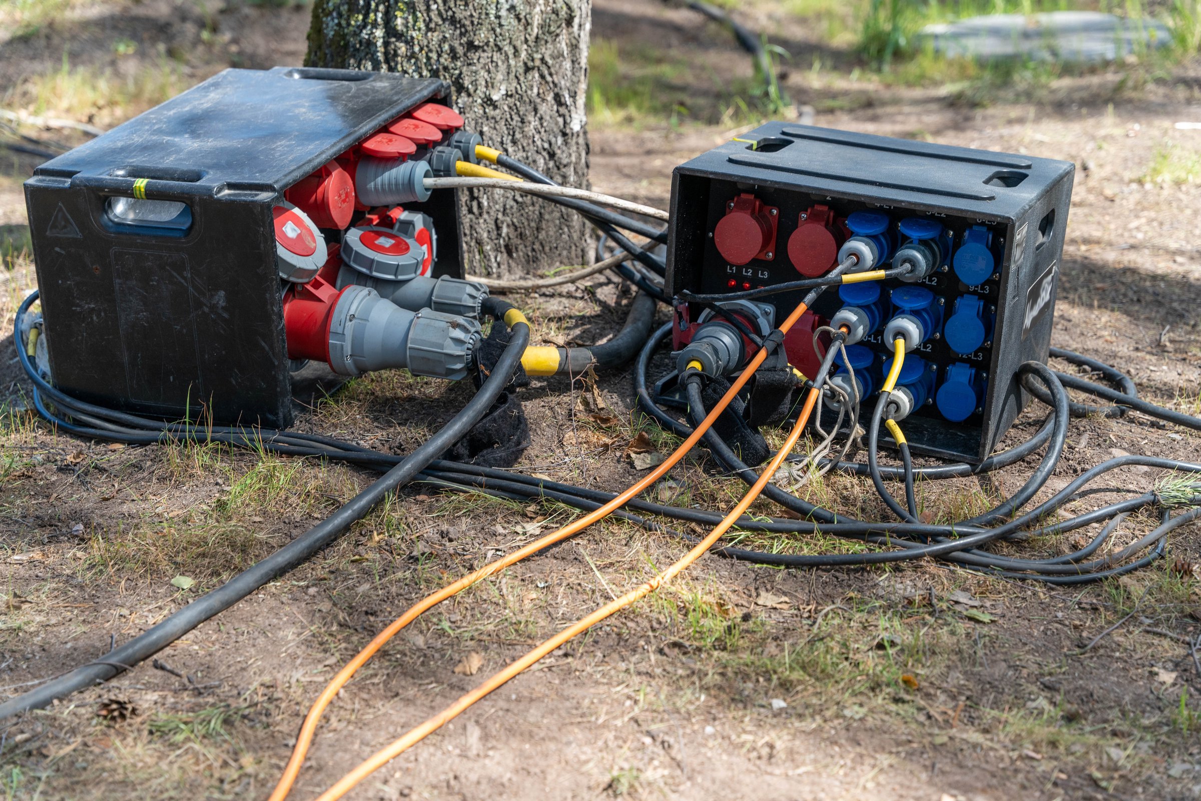 Portable power distribution boxes and cables providing electricity at an outdoor event setup