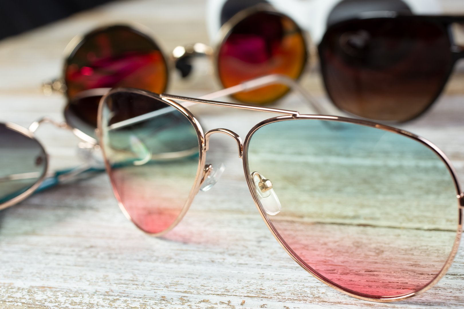 A closeup view of several cool sunglasses on a wooden surface.