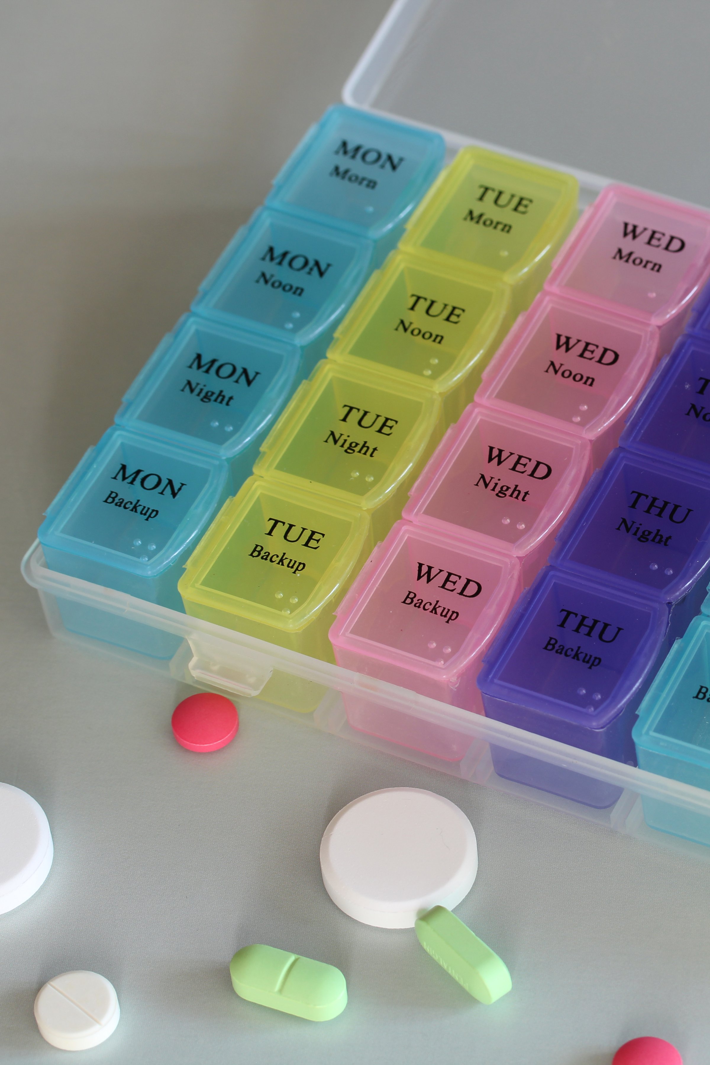 Weekly pill organizer displaying compartments for morning, noon, night, and backup doses, along with various pills