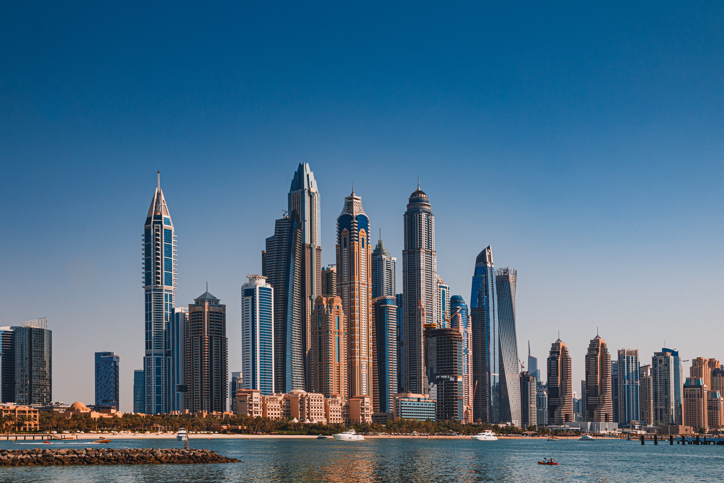 The sky reflected on modern glass skyscrapers and the sea as seen from the Palm Dubai. The buildings in the photo are located in Dubai Marina