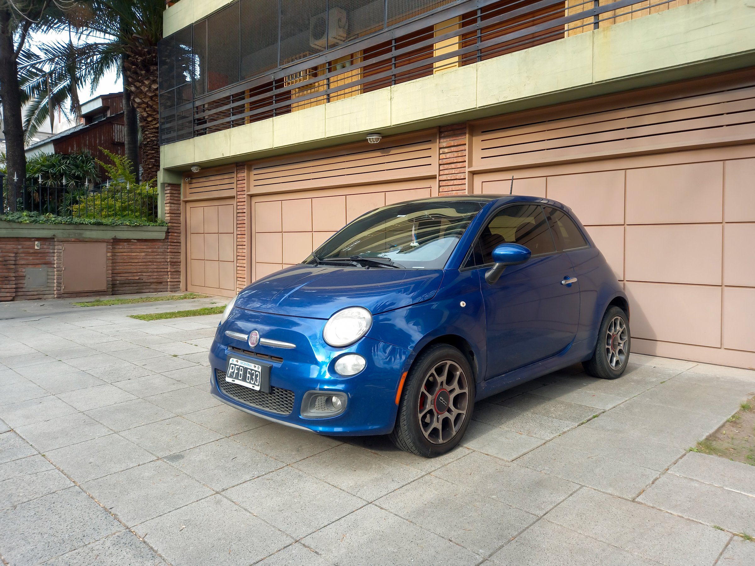 Buenos Aires, Argentina - Jul 29, 2025: Modern blue Fiat 500 Sport on the sidewalk out of a garage gate