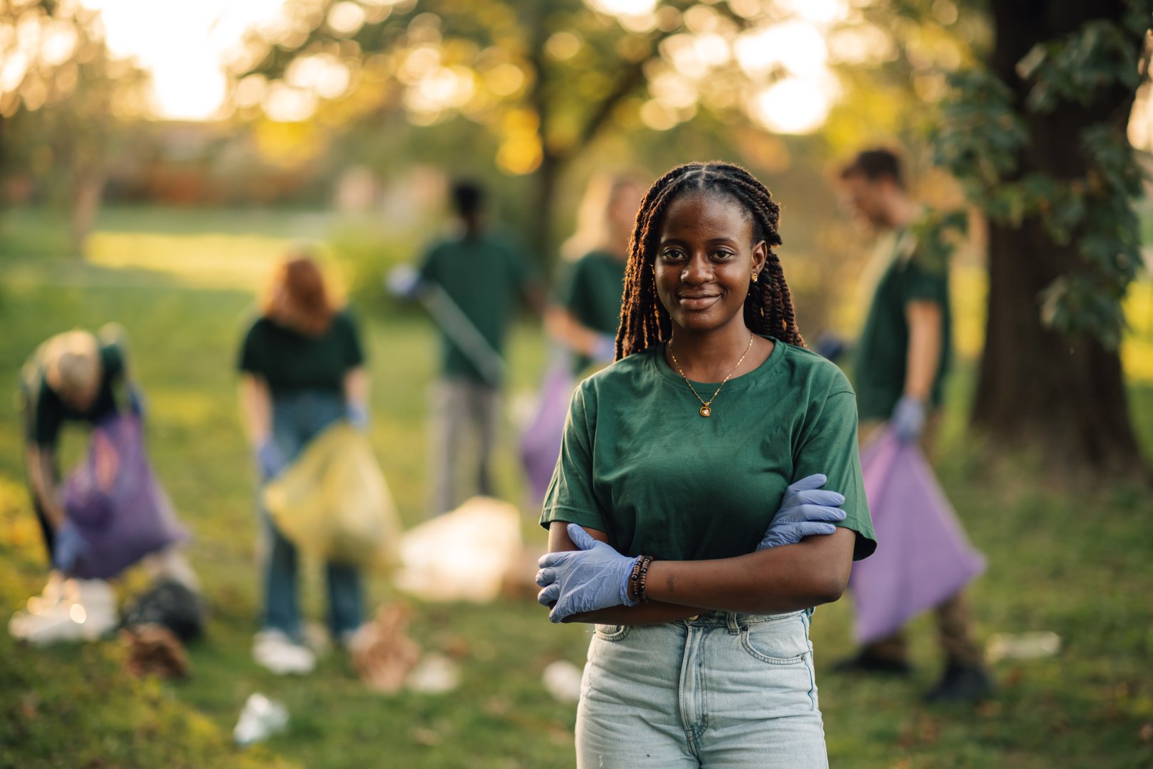Confident young woman volunteer leads a team cleaning up trash in a park, promoting community service and environmental responsibility