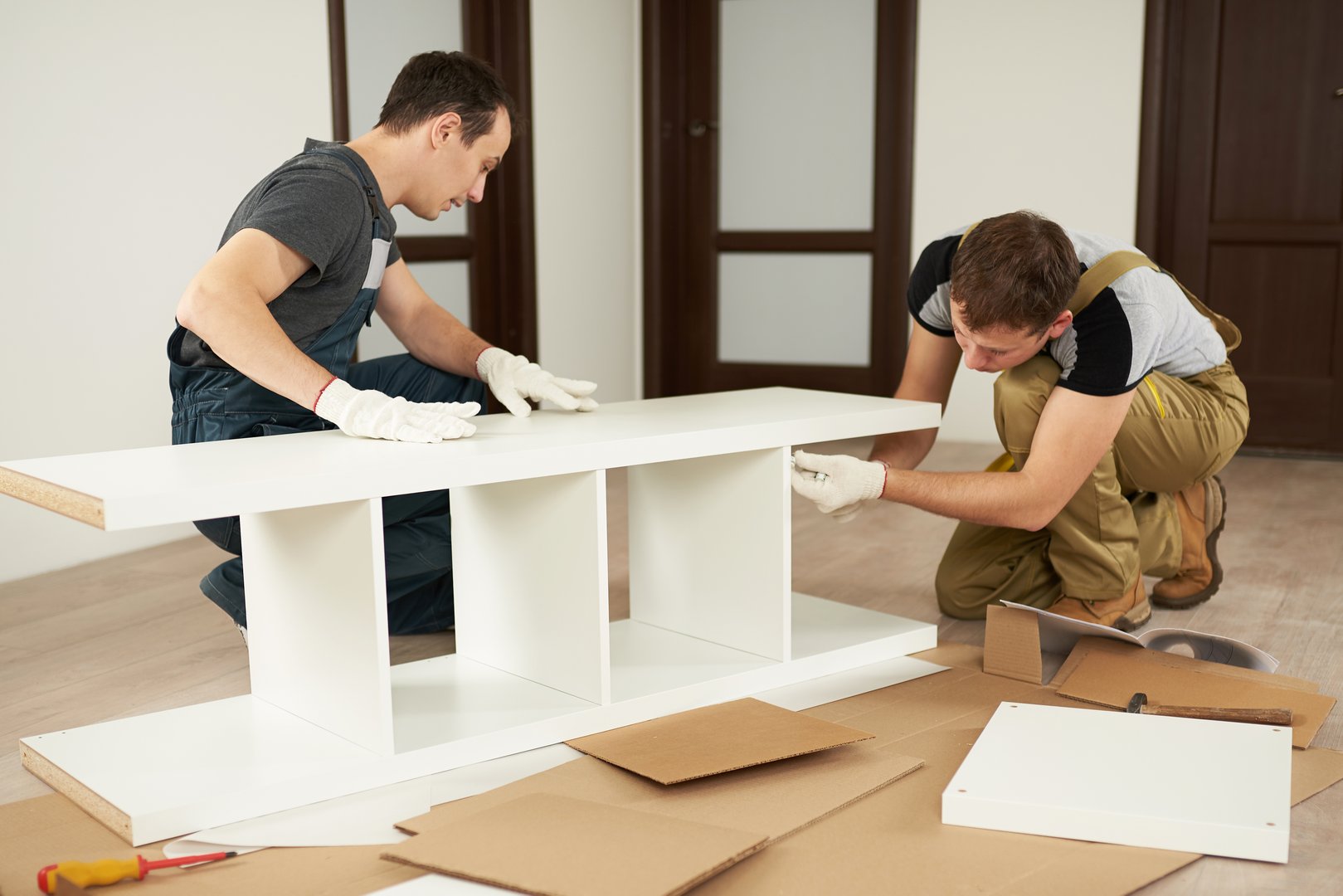 Two carpenters assembling furniture in house