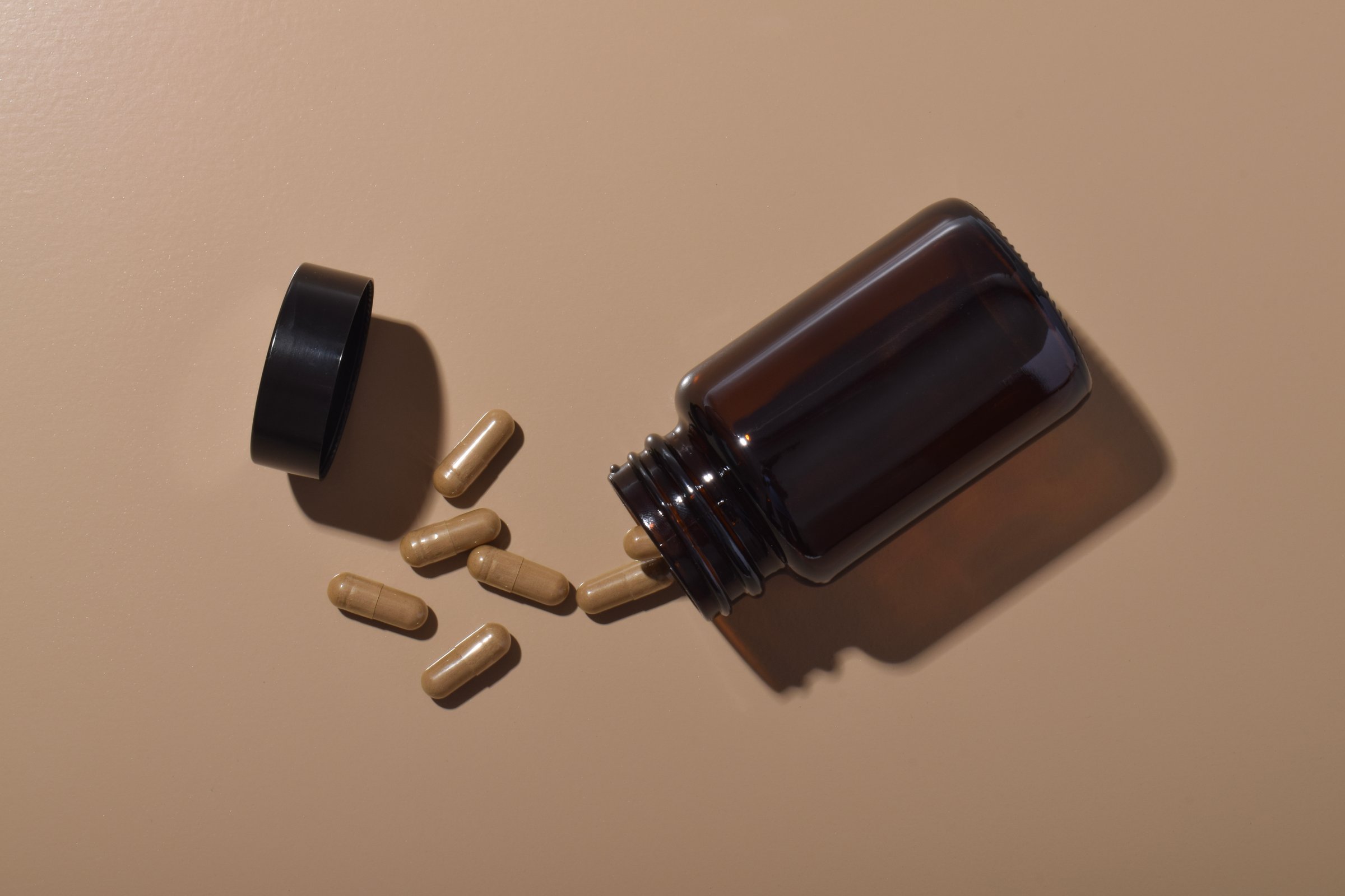 Capsules spilling from a bottle on a brown background. Healthcare and pharmacy. Medical treatment pills. Pharmaceutical industry and medicine.
