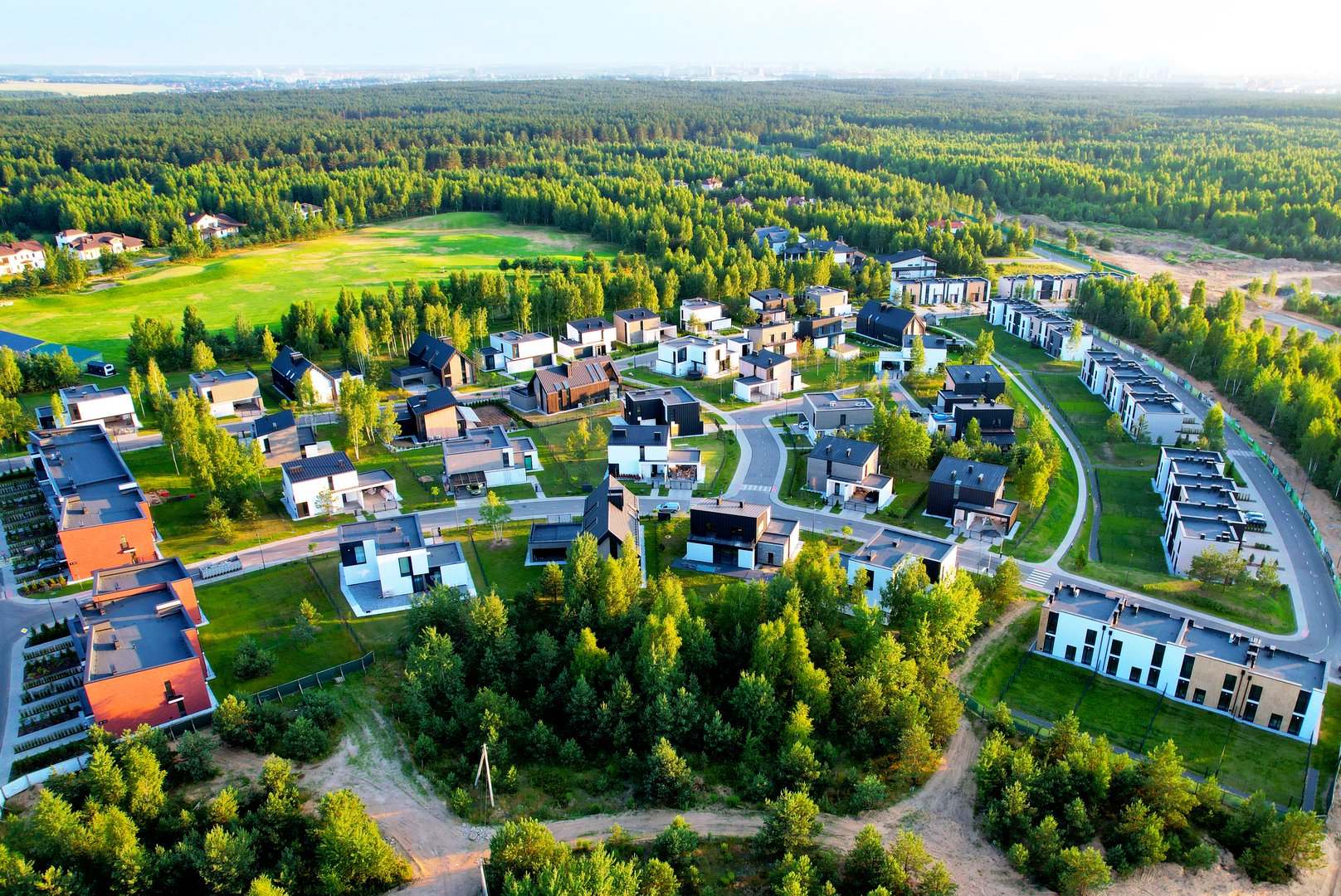 Aerial view of the roofs of modern houses. Cottages, townhouses and line houses. Modern residential complex. Roofs of suburban private houses in forest area.