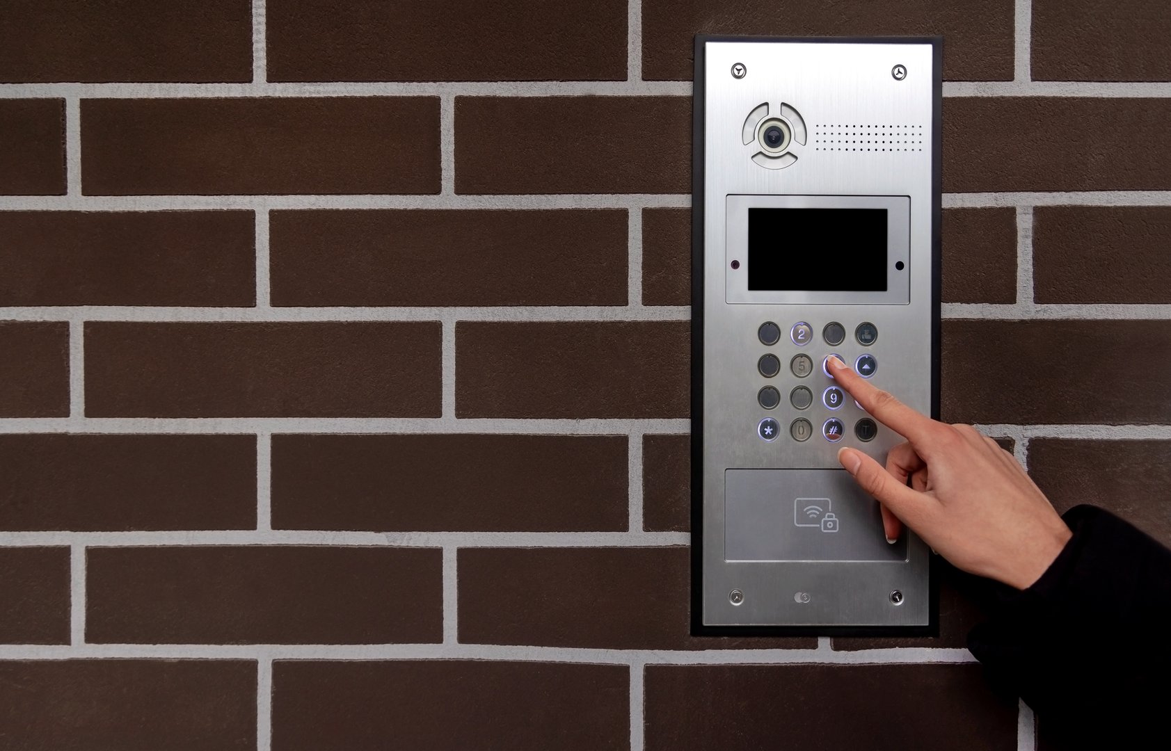 Hand entering code on keypad at building entrance