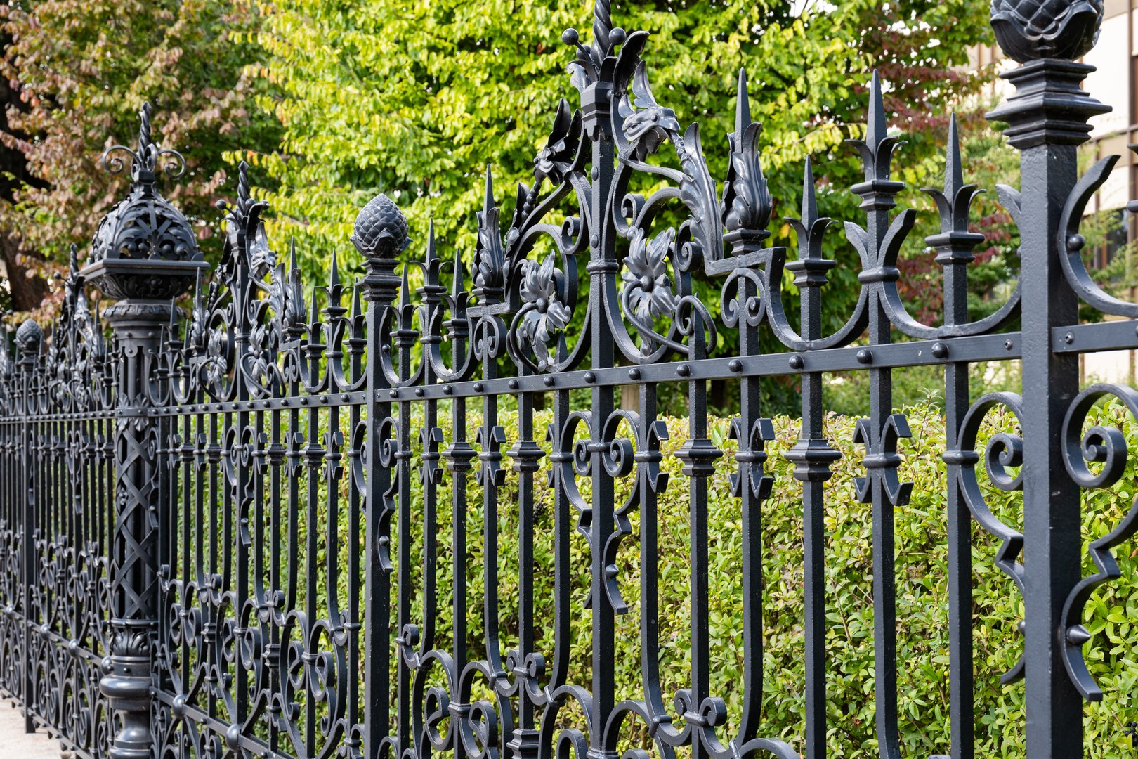 Wrought iron fence around a park. Side view, sunny summer day, no people.