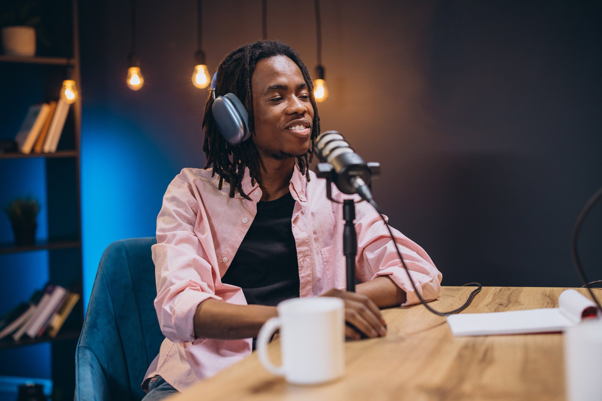 African American podcaster recording radio show, wearing headphones while speaking into professional microphone