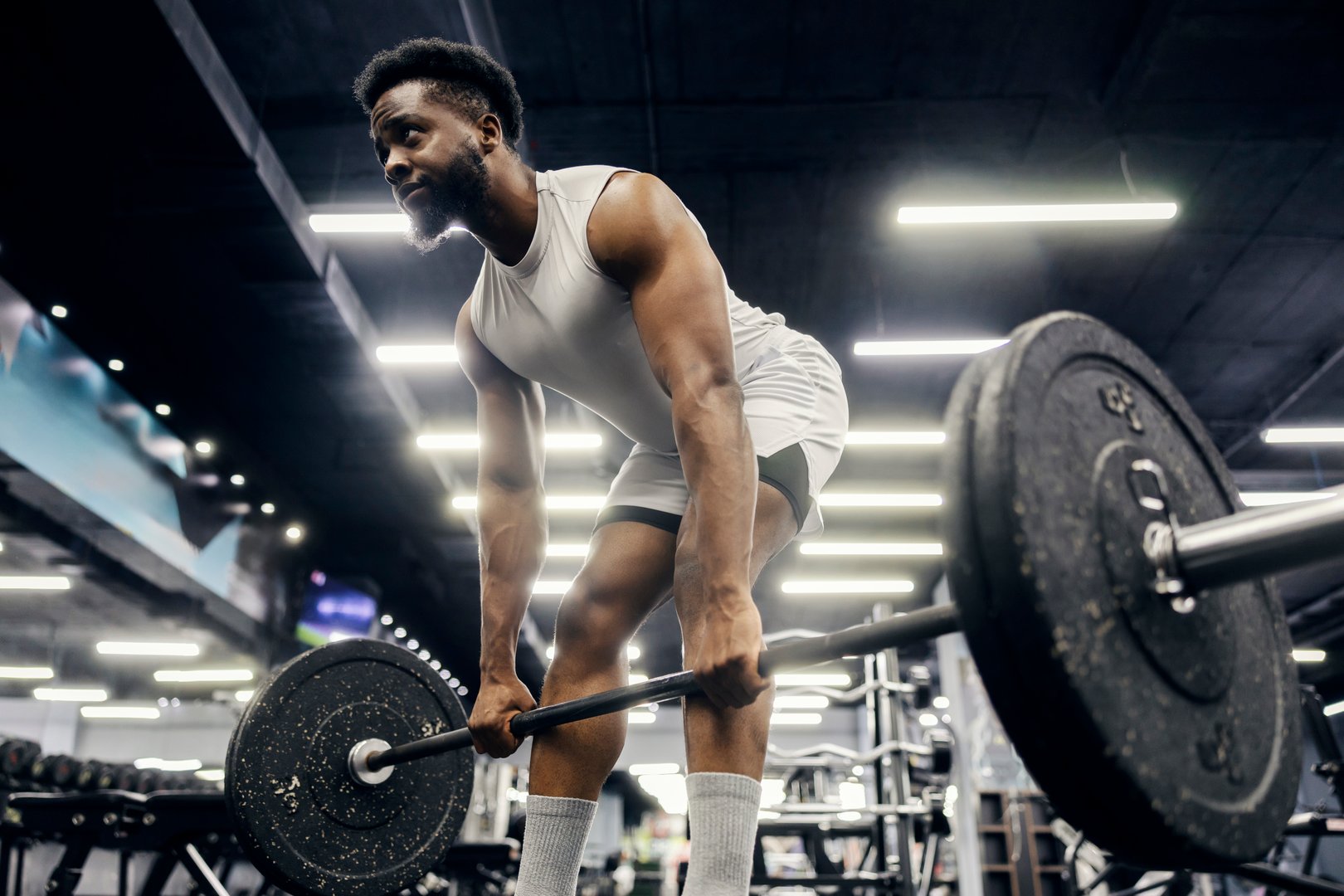 Young man doing a deadlift exercise with a heavy barbell in a modern gym, focusing on strength training and fitness