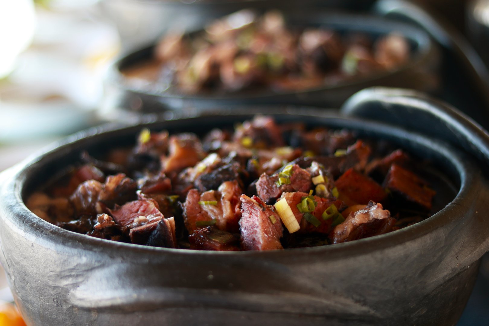 Traditional Brazilian Feijoada served in authentic black clay pots on a buffet table.