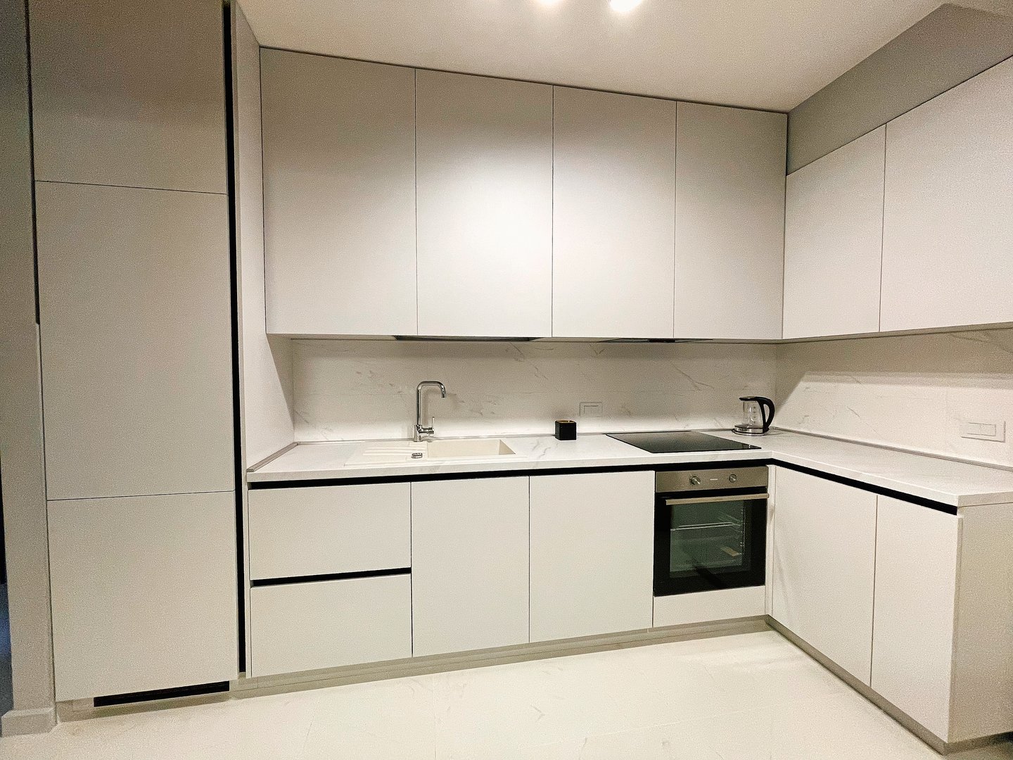 Modern minimalist kitchen design showcasing sleek white cabinetry, integrated appliances, and a spacious layout ideal for contemporary living and cooking.