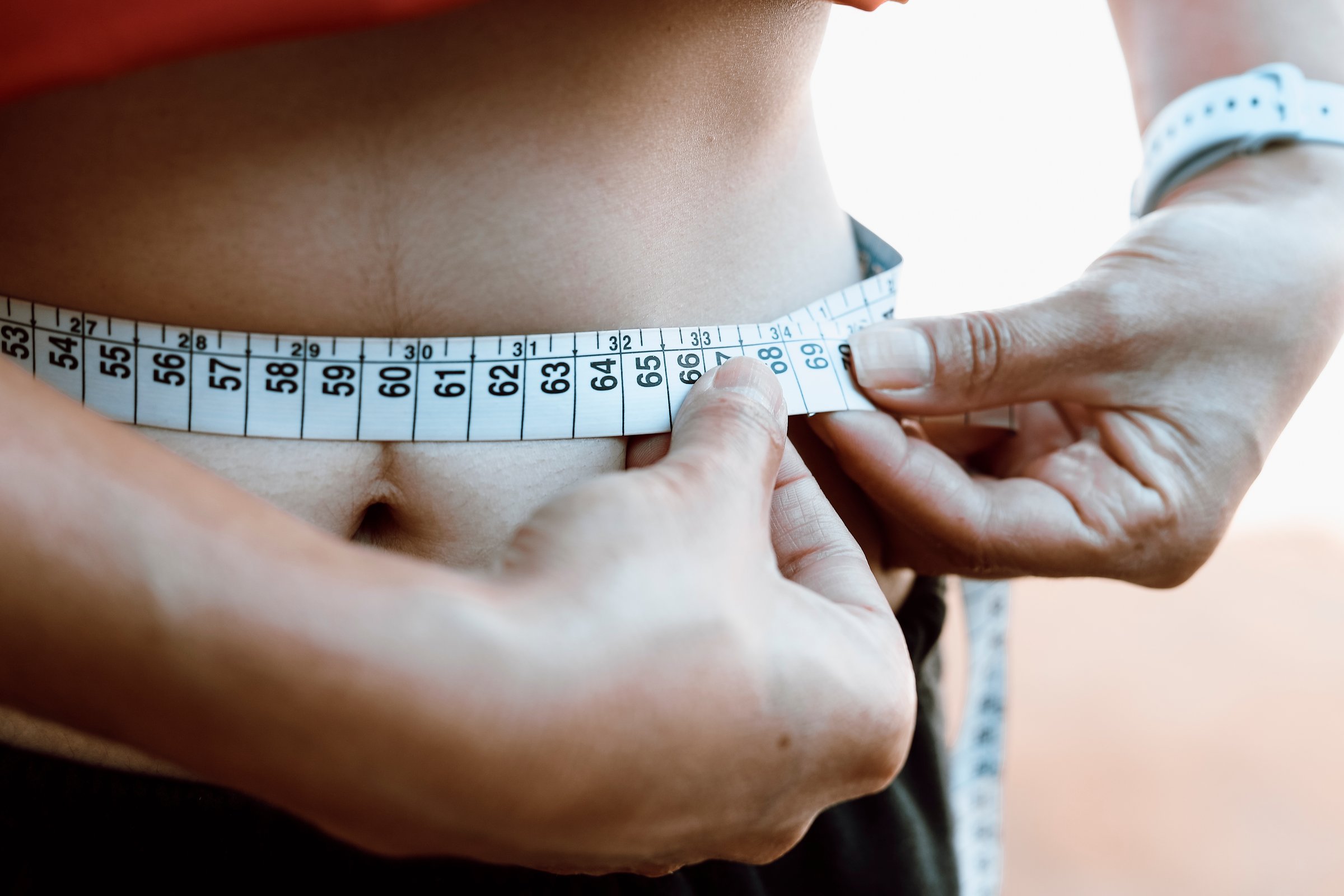 A woman takes her waist measurements with a measuring tape. According to the World Health Organization (WHO), 12.5% of the world's population is considered obese