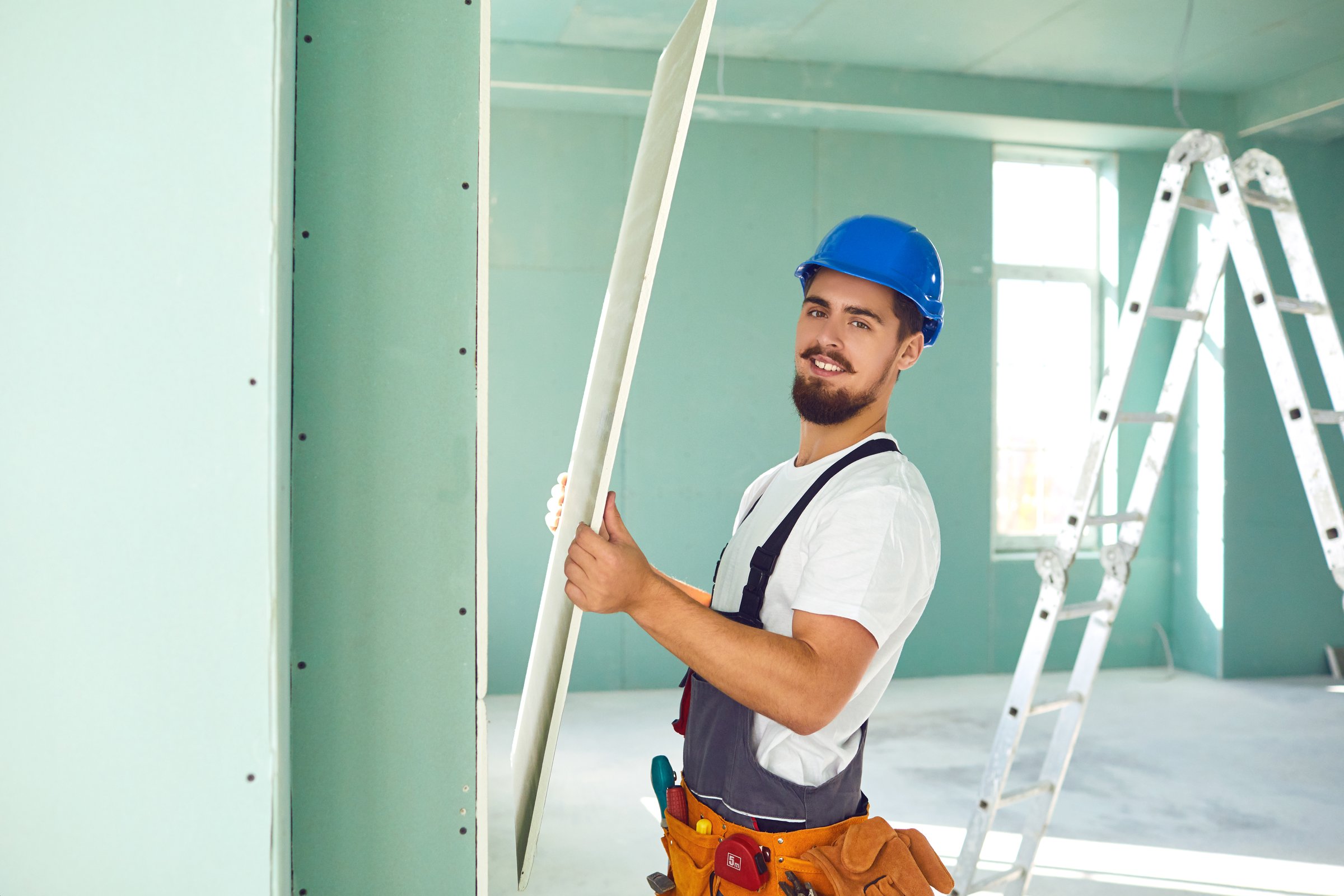 Worker builder installs plasterboard drywall at a construction site office open space