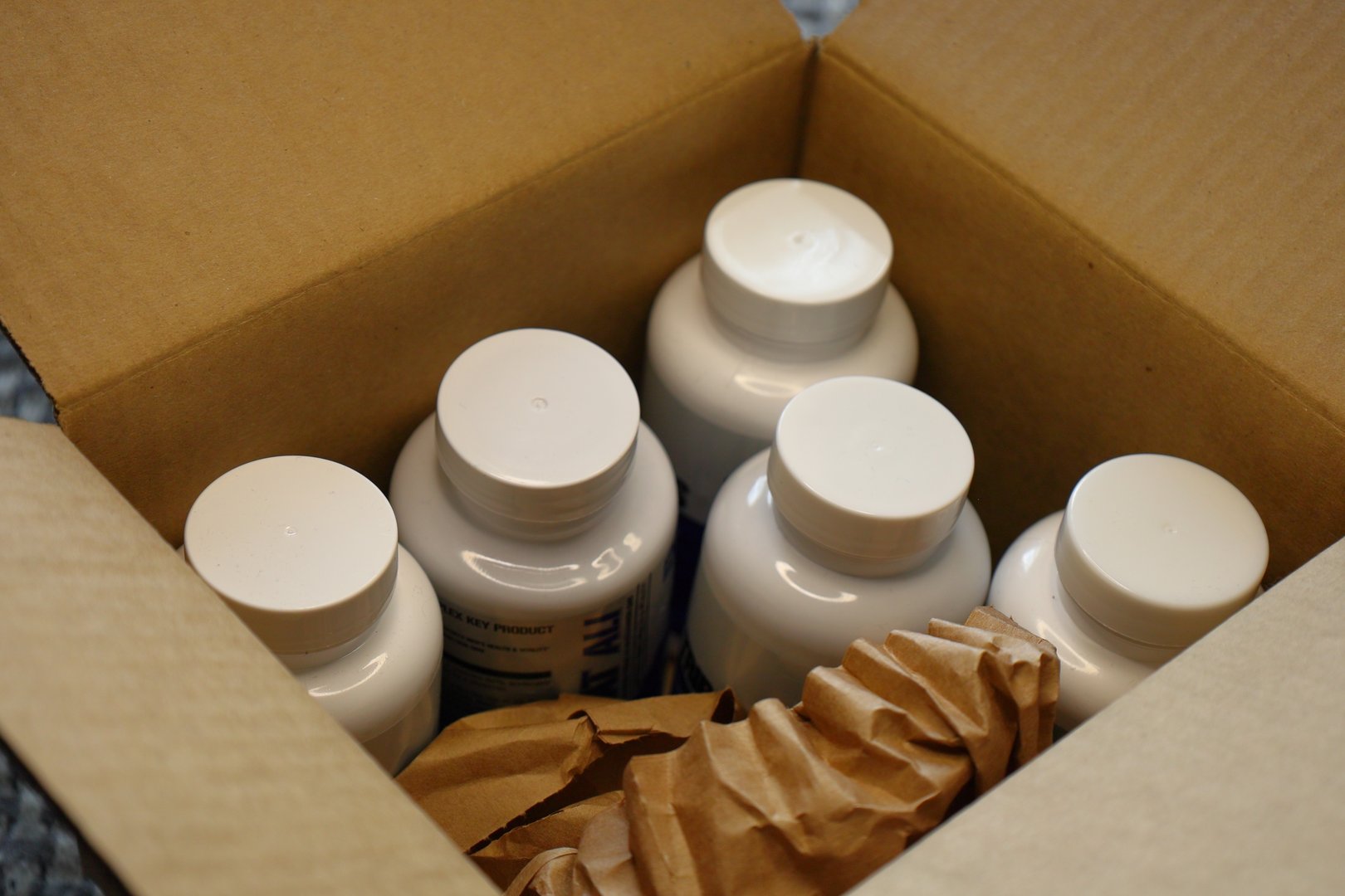a box with five white plastic bottles and packing paper inside.