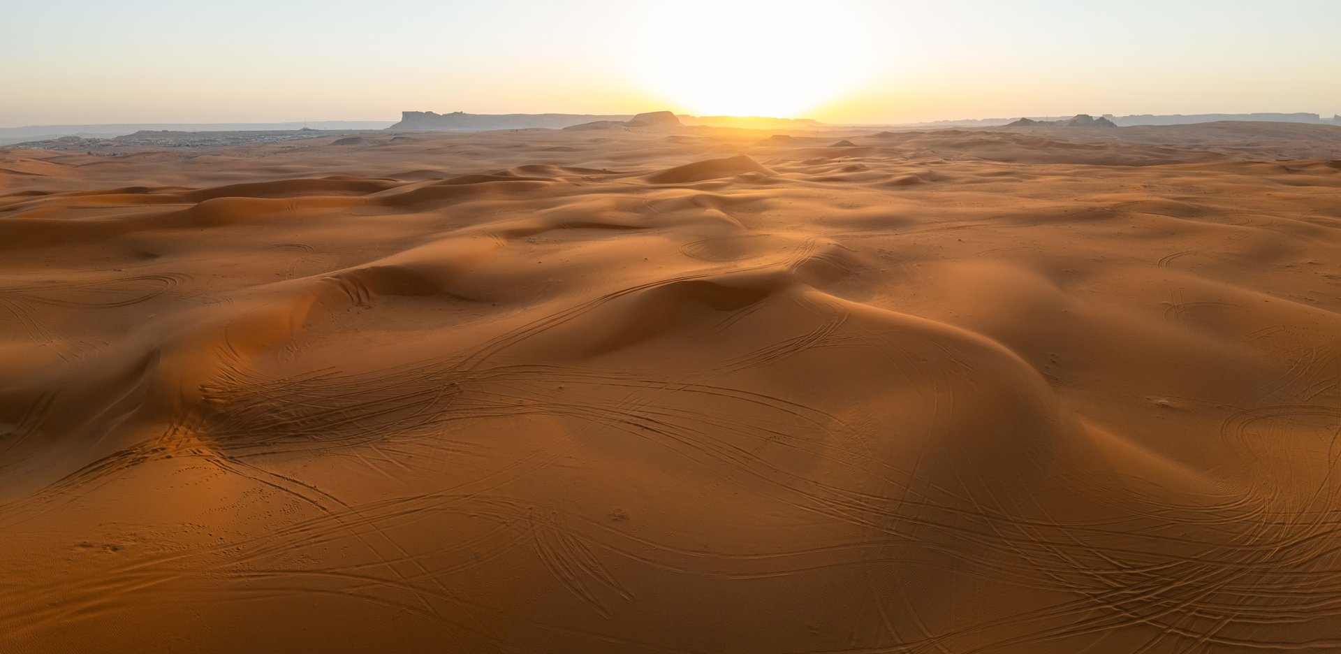 Sunrise Over the Saudi Desert Captured by Drone. Golden rays of the rising sun illuminate the rolling dunes of the Saudi desert in this breathtaking aerial view. The smooth curves of the landscape come alive with light and shadow, evoking serenity, stillness, and natural beauty. This drone footage captures the peaceful majesty of dawn in one of the world's most iconic landscapes. High-quality photo