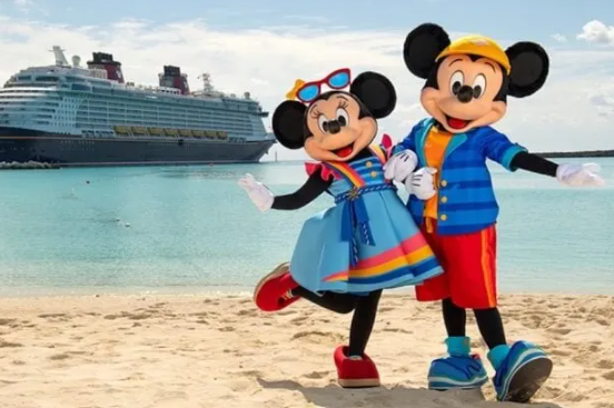 Mickey and Minnie Mouse in beach attire posing on a sandy beach with a cruise ship in the background.