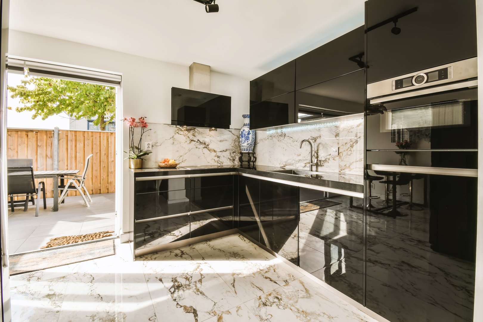 a black and white kitchen with marble counter tops on the island in front of the sink is seen through an open door