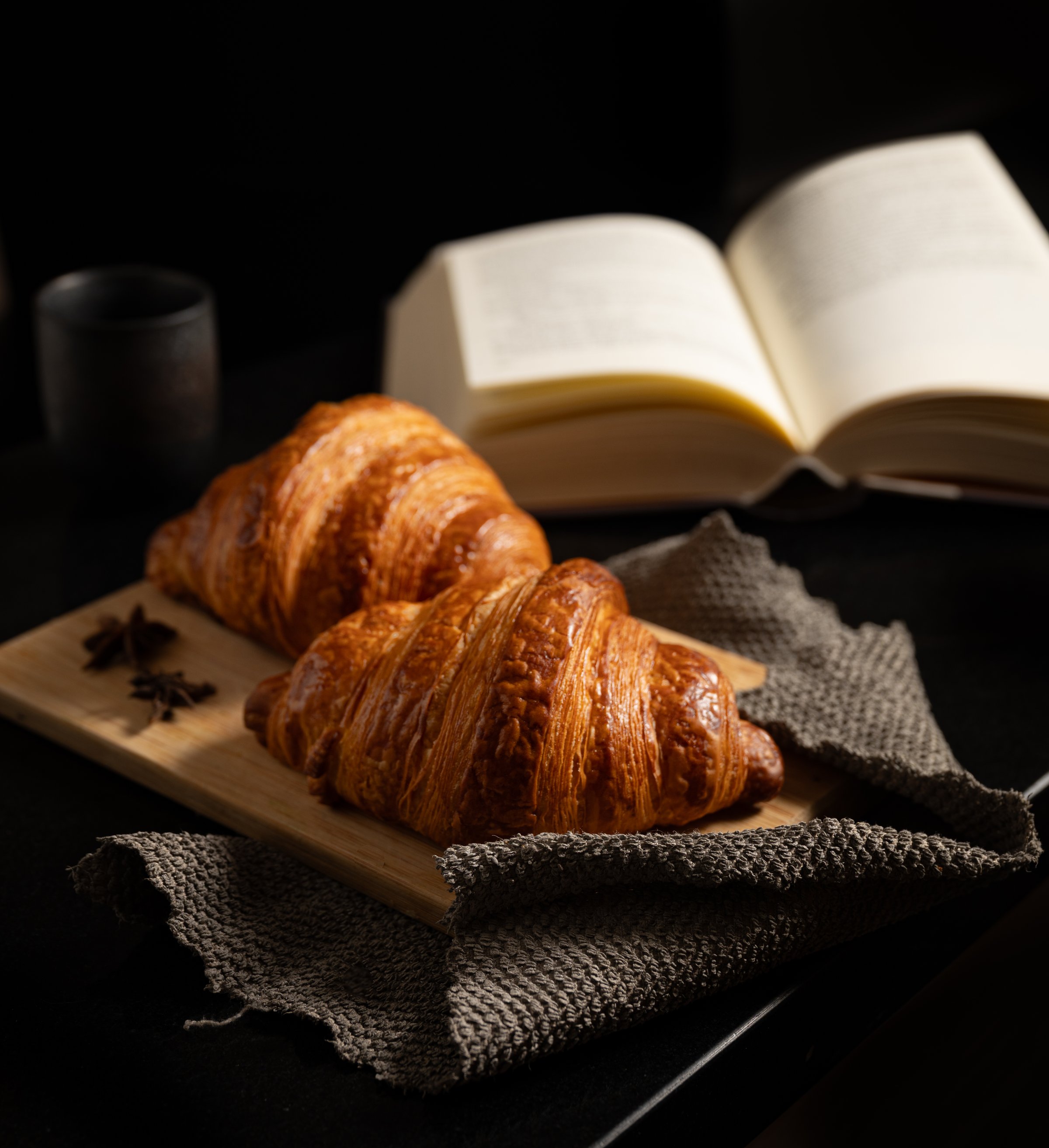 Golden flaky croissant with well-defined layers accented by star anise
