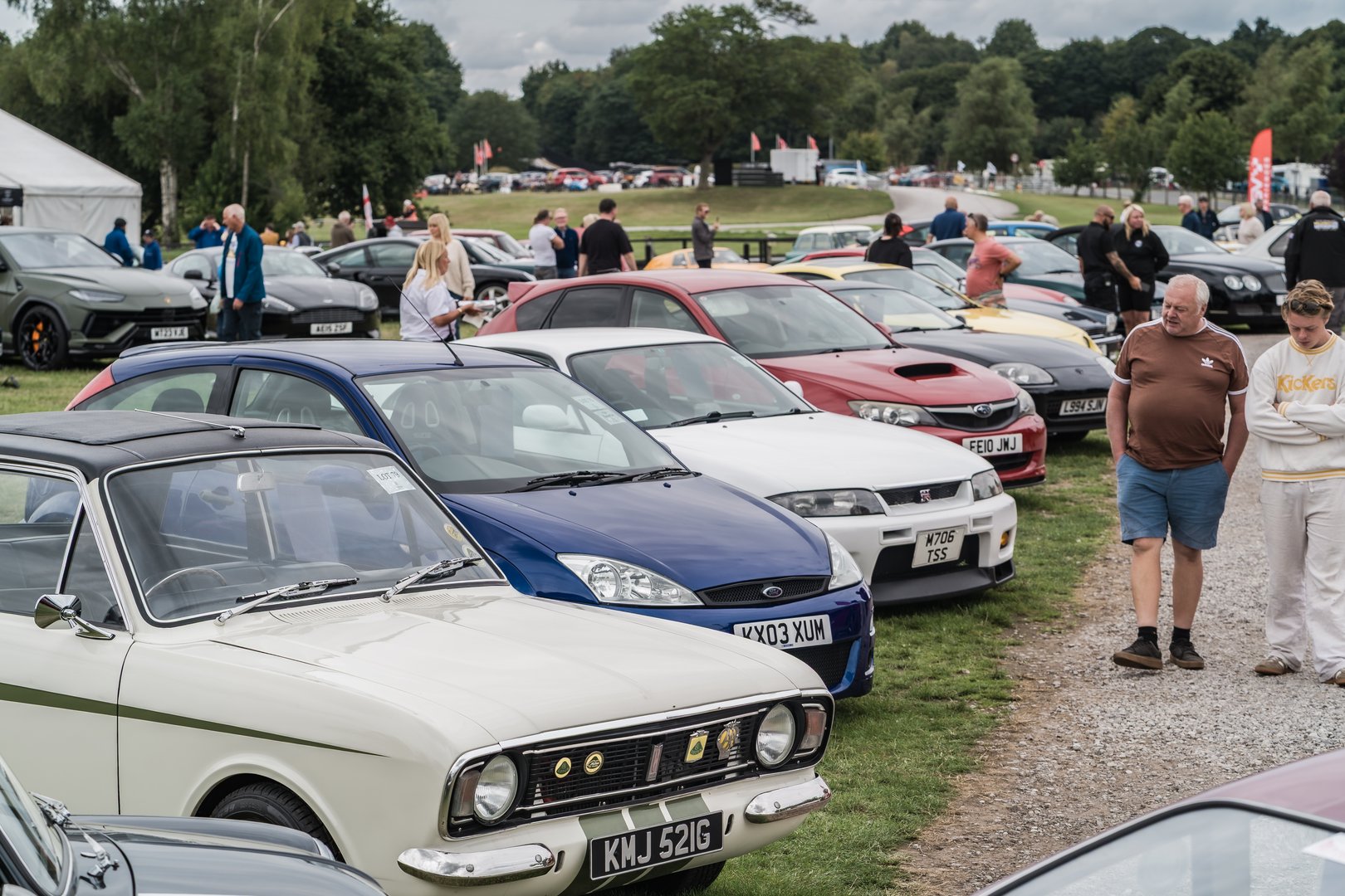 Tarporley, Cheshire, England, July 27th 2025. A row of cars are displayed at the Tarporley Classic Car Auction, with people browsing vehicles in the background.