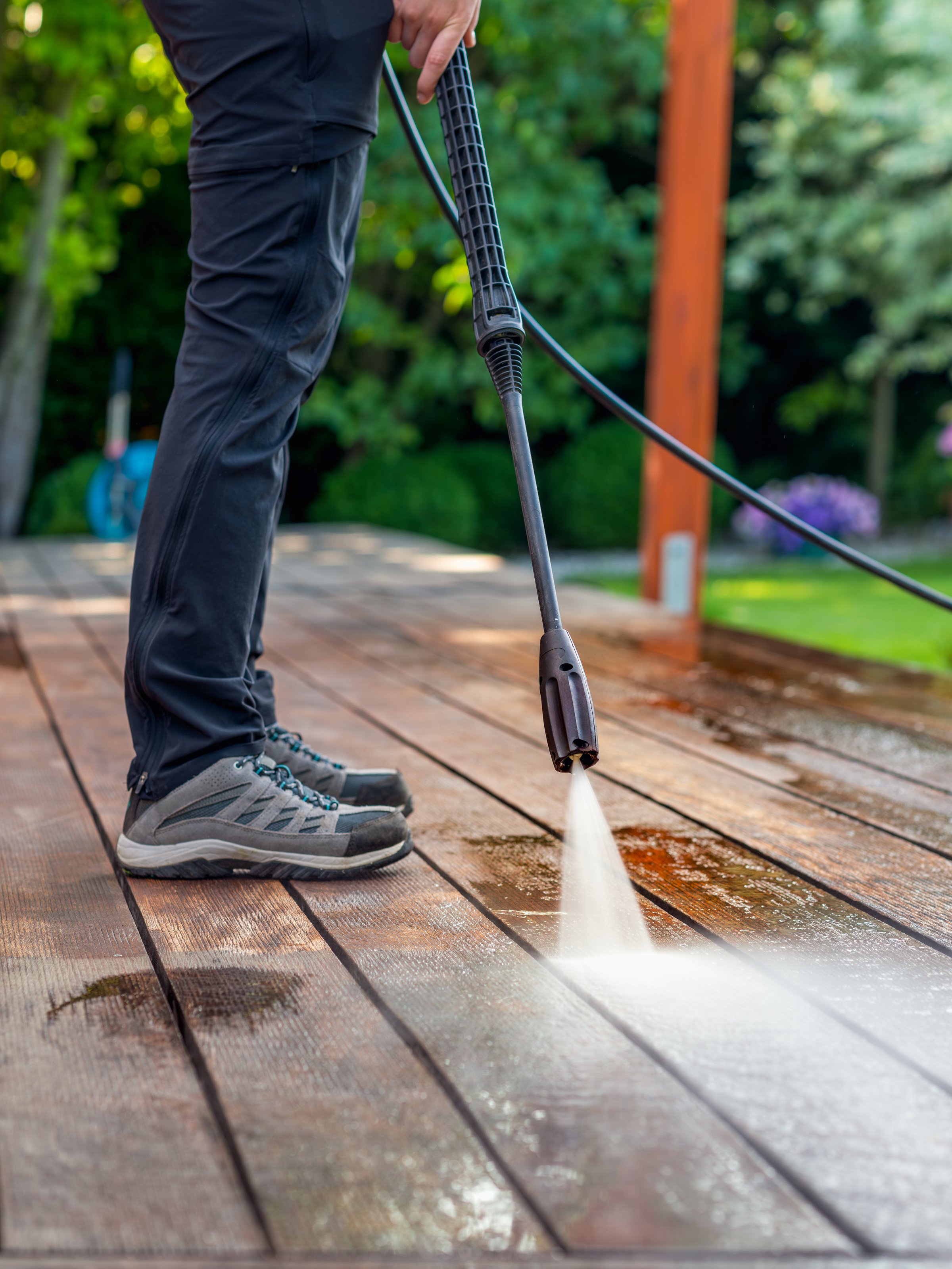 cleaning the terrace with a pressure washer - high-pressure cleaner on the wooden surface of the terrace - very shallow depth of field - sharpness on the terrace board under a stream of water