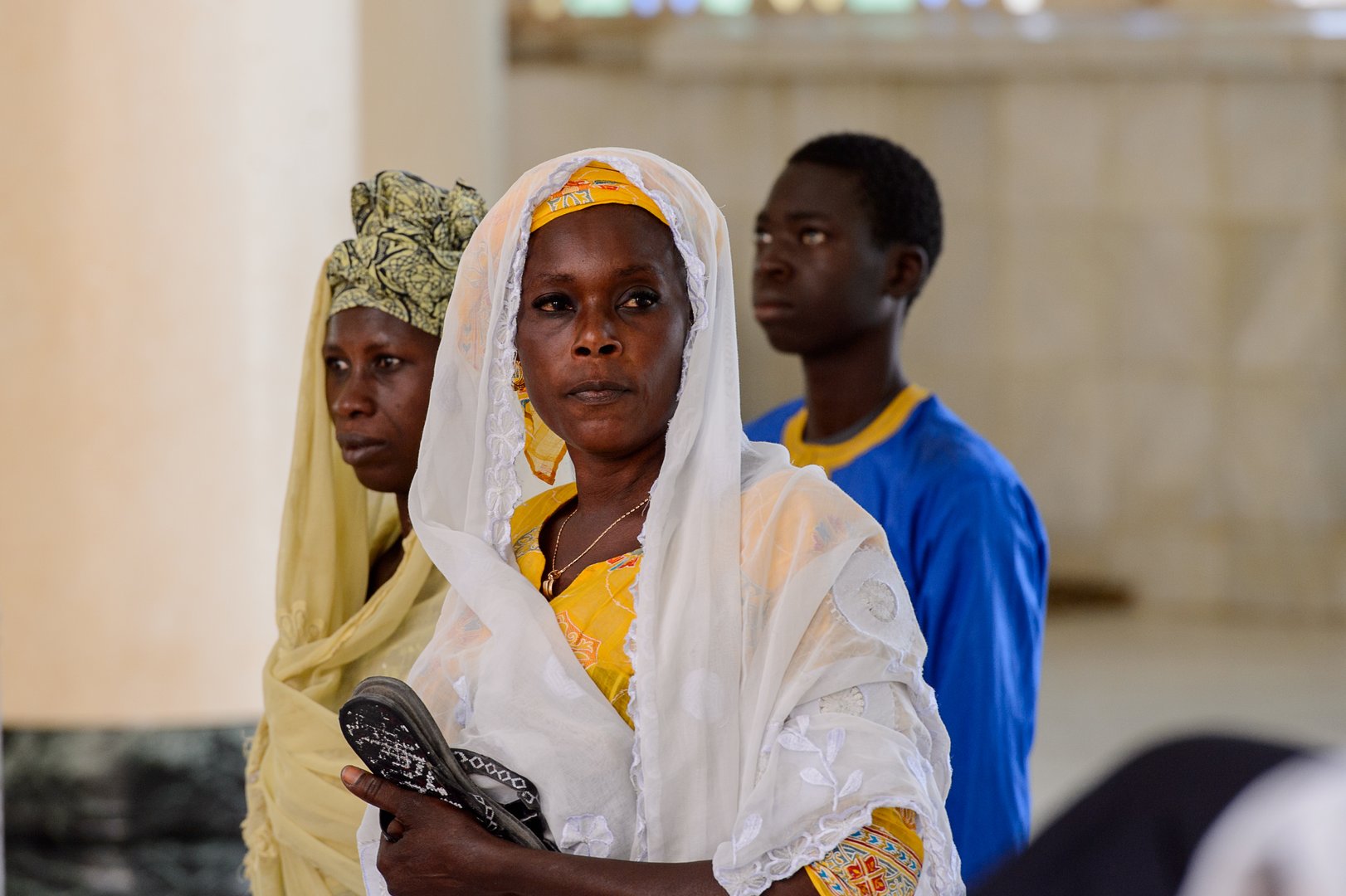 TOUBA, SENEGAL - APR 26, 2017: Unidentified Senegalese women in colored traditional clothes and headscarves walk in the Great Mosque of Touba, the home of the Mouride Brotherhood