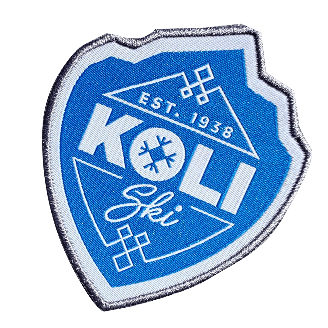Blue and white embroidered patch with EST. 1938 KOLI Ski and snowflake symbols on a shield-shaped design.
