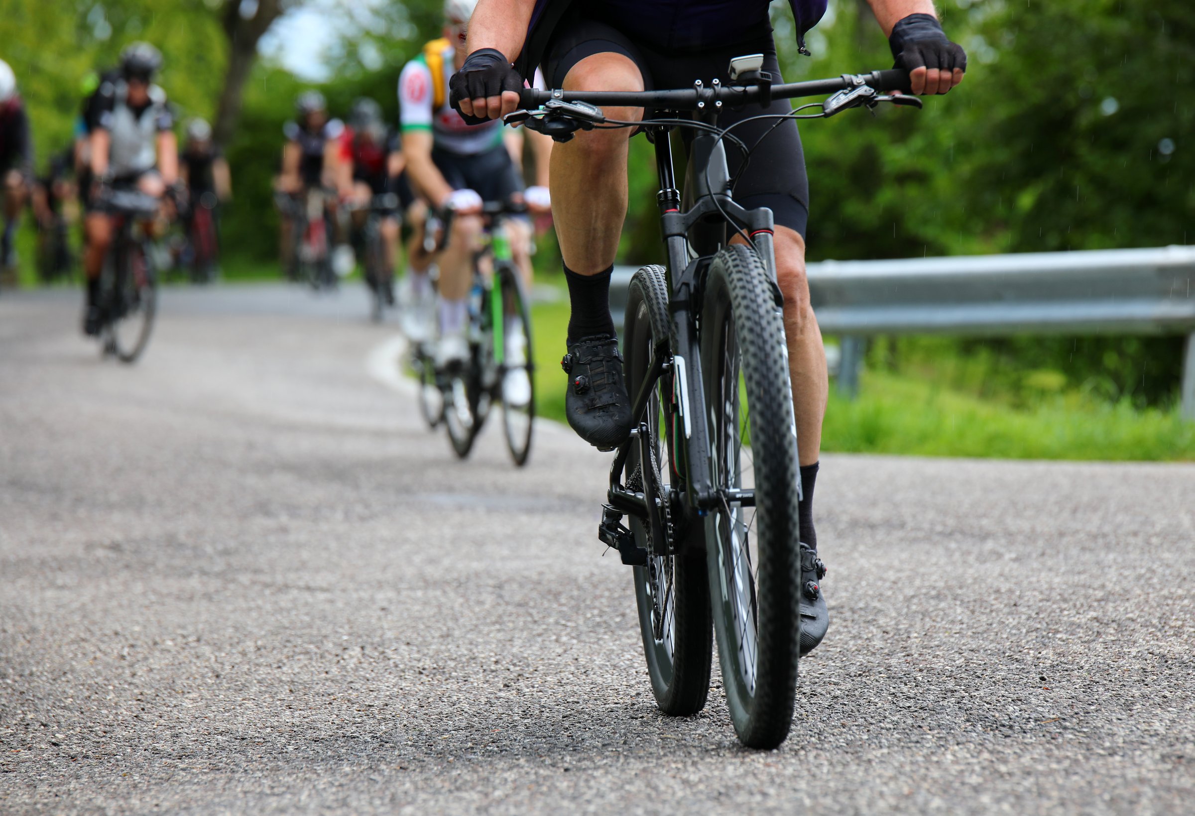 Gravel bike racing on mixed terrain with other cyclists in the background