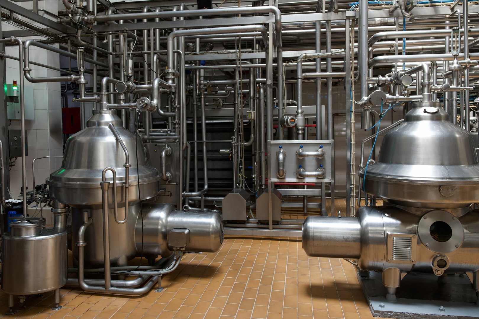 Large stainless steel milk separators and intricate piping systems are displayed in a modern industrial processing facility, highlighting advanced machinery and engineering excellence