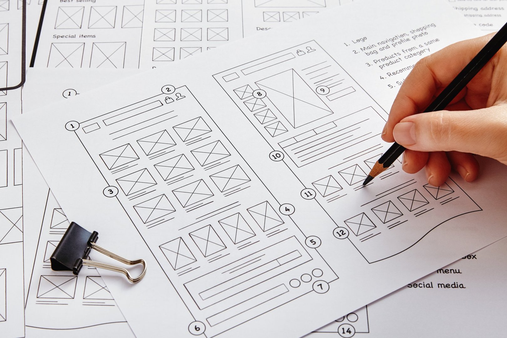 Web design project concept. Close up photo of a UX designer working on website project with a large number of wireframe sketches.