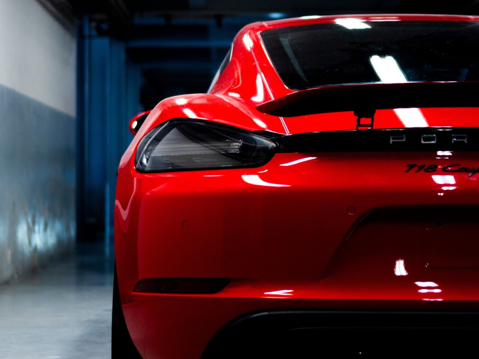 Rear view of a red sports car in a dimly lit garage, highlighting its sleek design and tail light.
