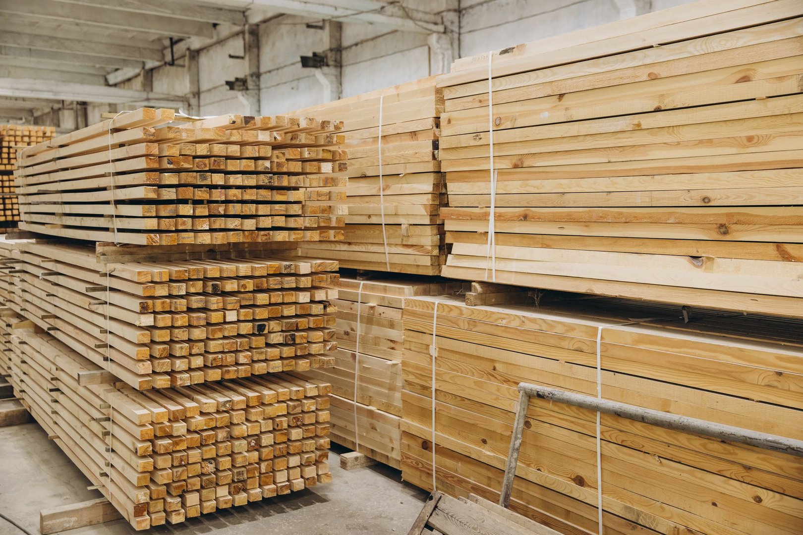 Large stacks of timber planks and square studs create an interesting geometric composition in a warehouse or lumber storage facility
