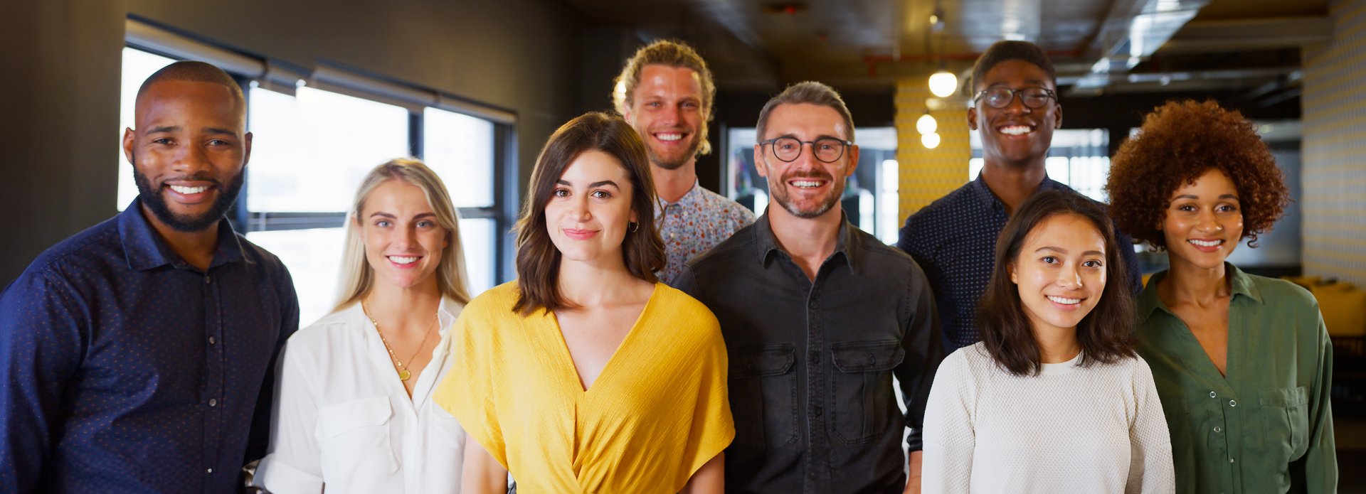 Portrait Of Smiling Multi-Cultural Business Team In Modern Open Plan Office Together
