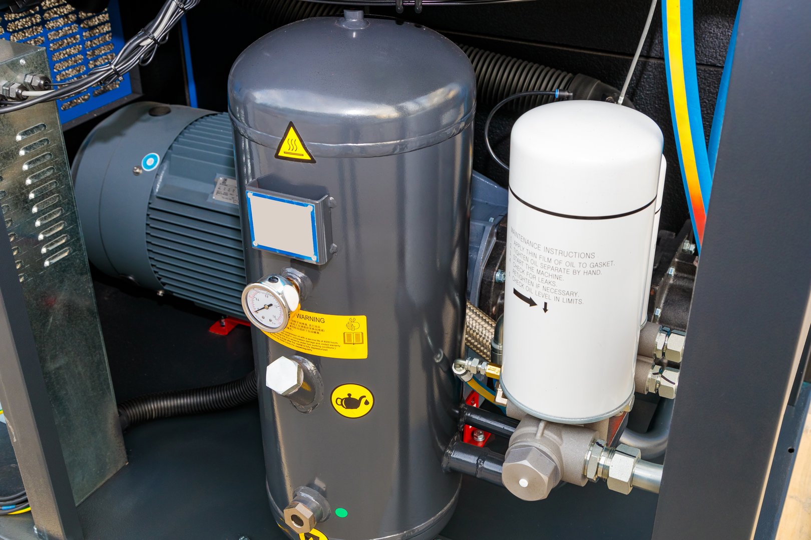 Close-up of an air compressor unit featuring motor, tank, filter, and various components