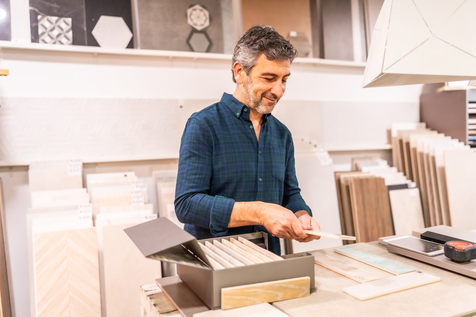 Mature man is carefully selecting tiles for his home renovation project in a home improvement store