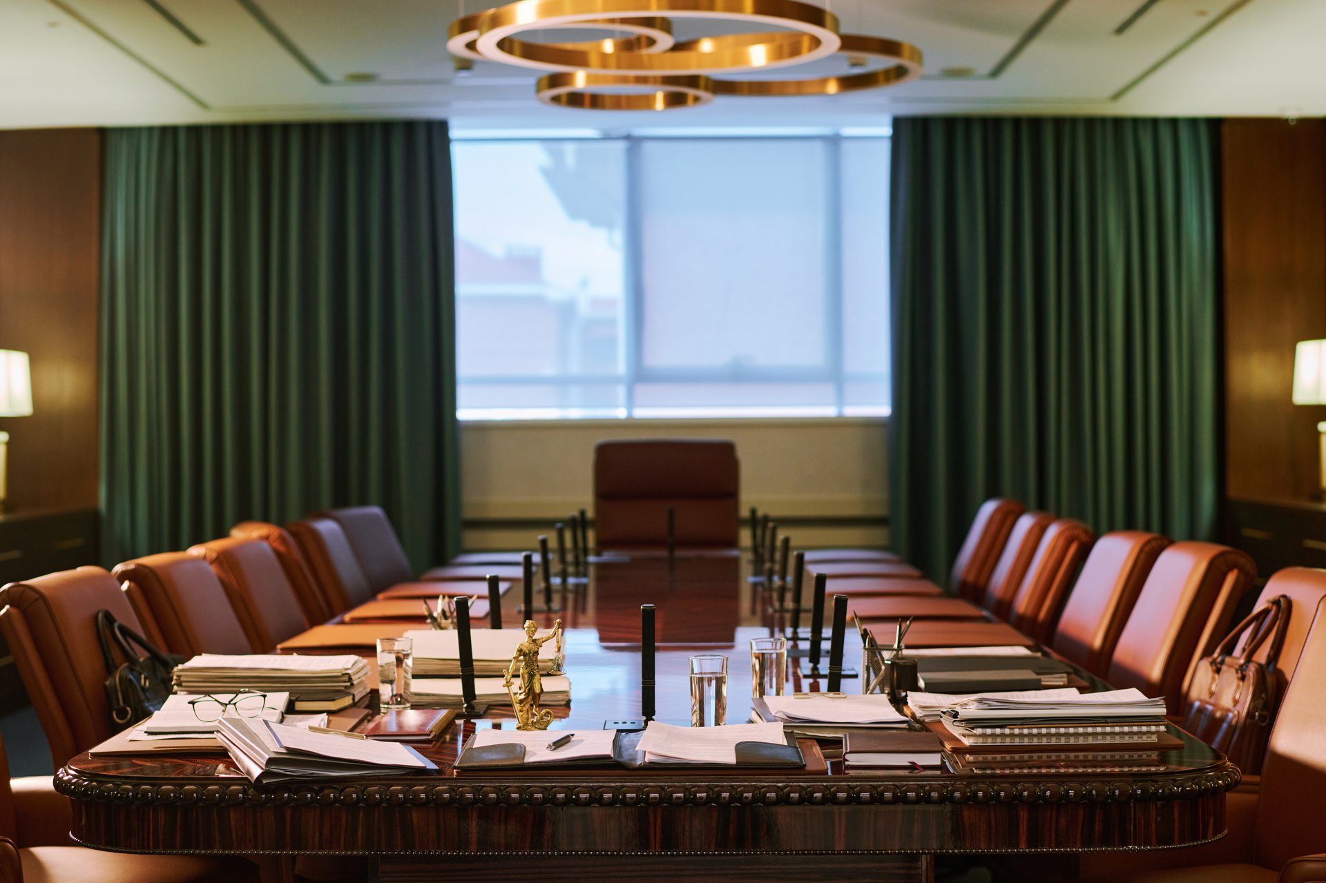 Group of brown leather armchairs surrounding long table with folders and paper documents standing in the center of spacious boardroom